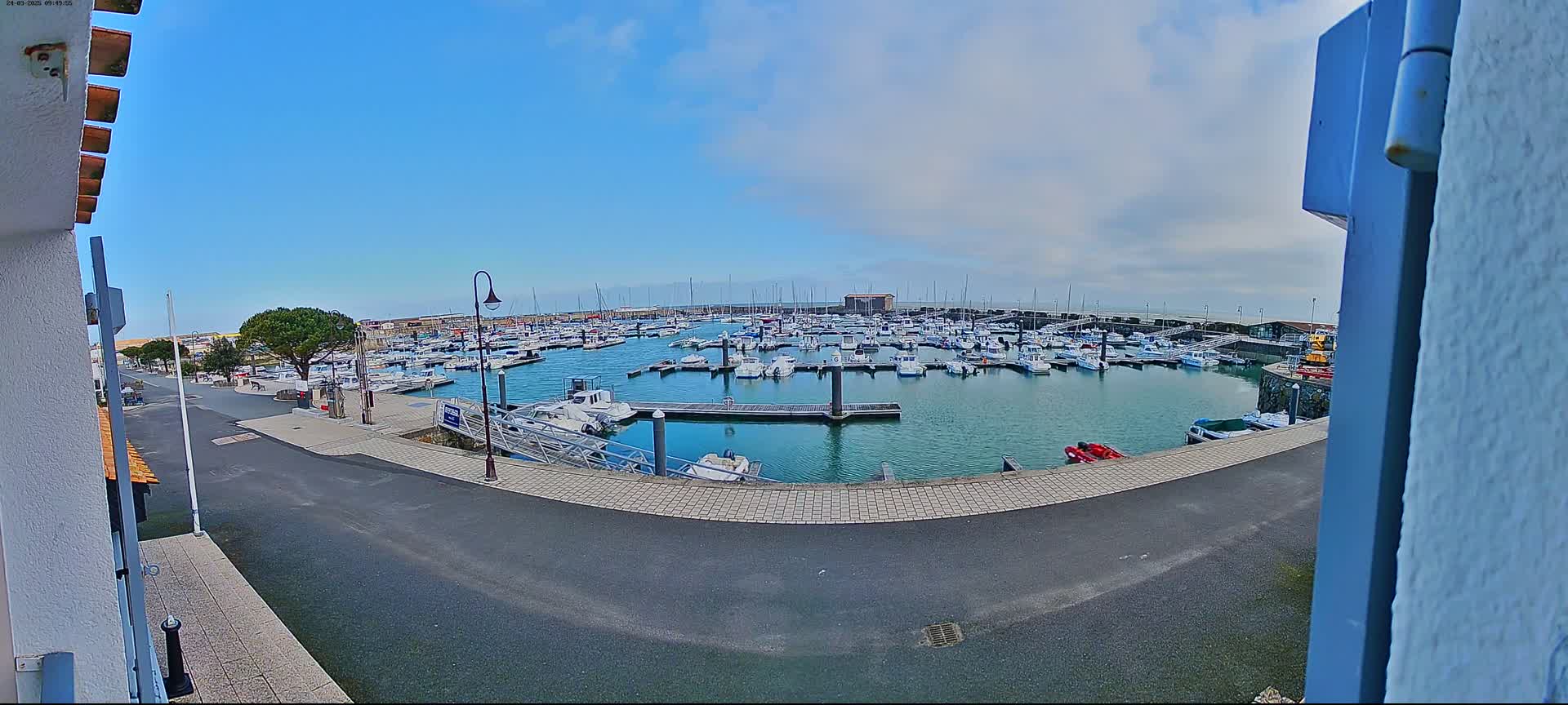 A marina filled with numerous boats is seen on a partly cloudy day.