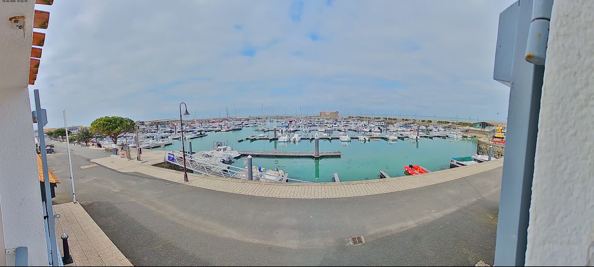 A marina filled with numerous boats is seen on a partly cloudy day.
