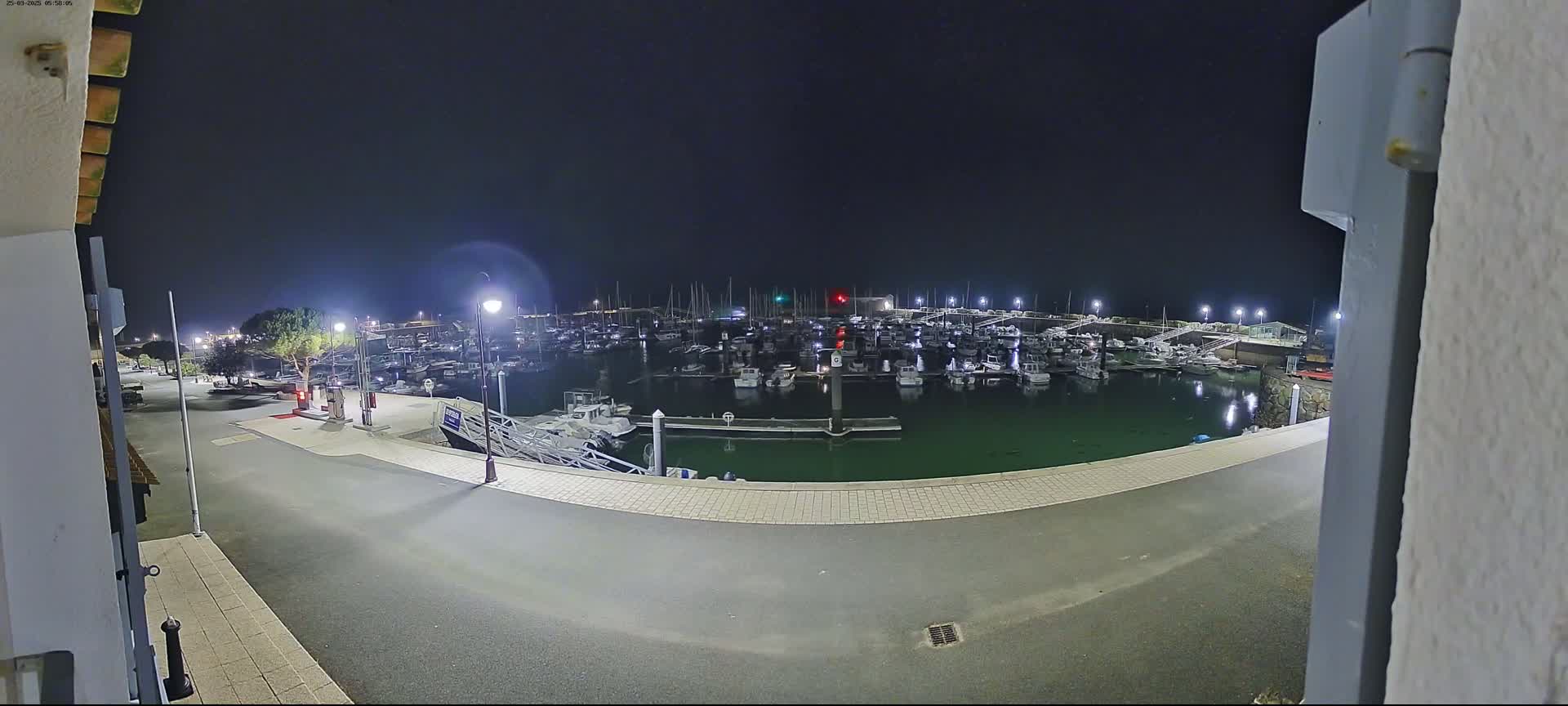 A nighttime view of a marina filled with numerous boats under a dark sky.