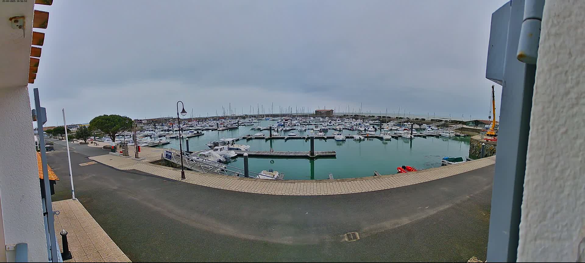 A marina filled with numerous boats is seen under an overcast sky.