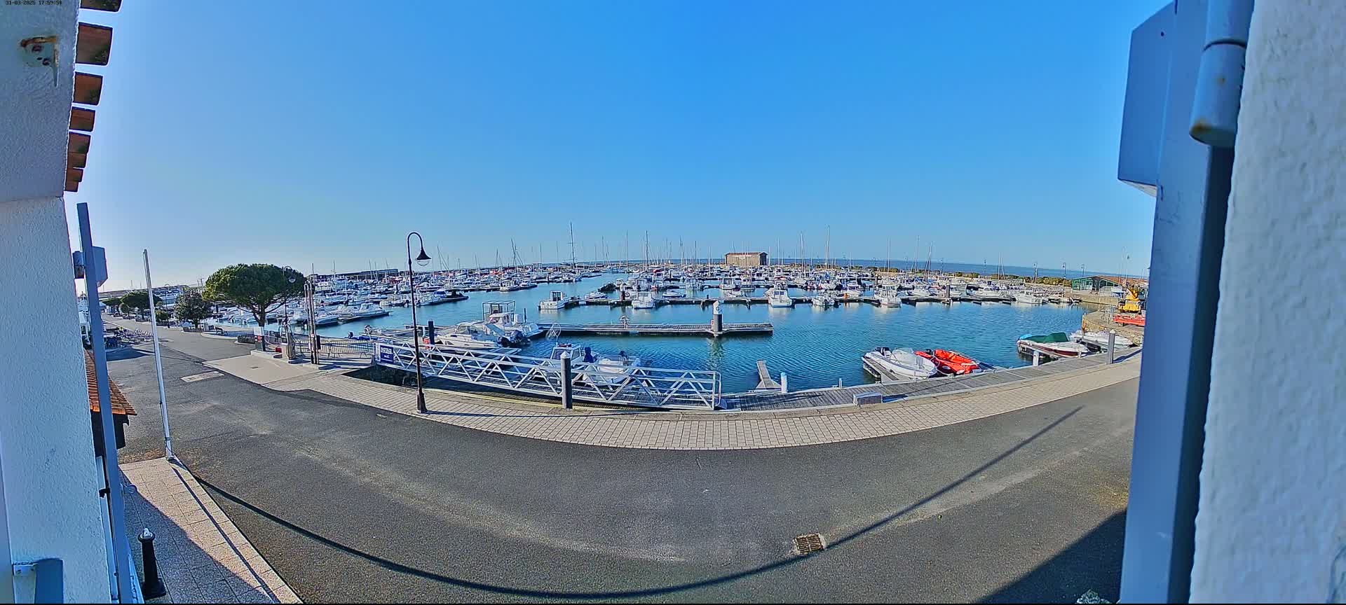 A marina filled with numerous boats is seen on a sunny day.