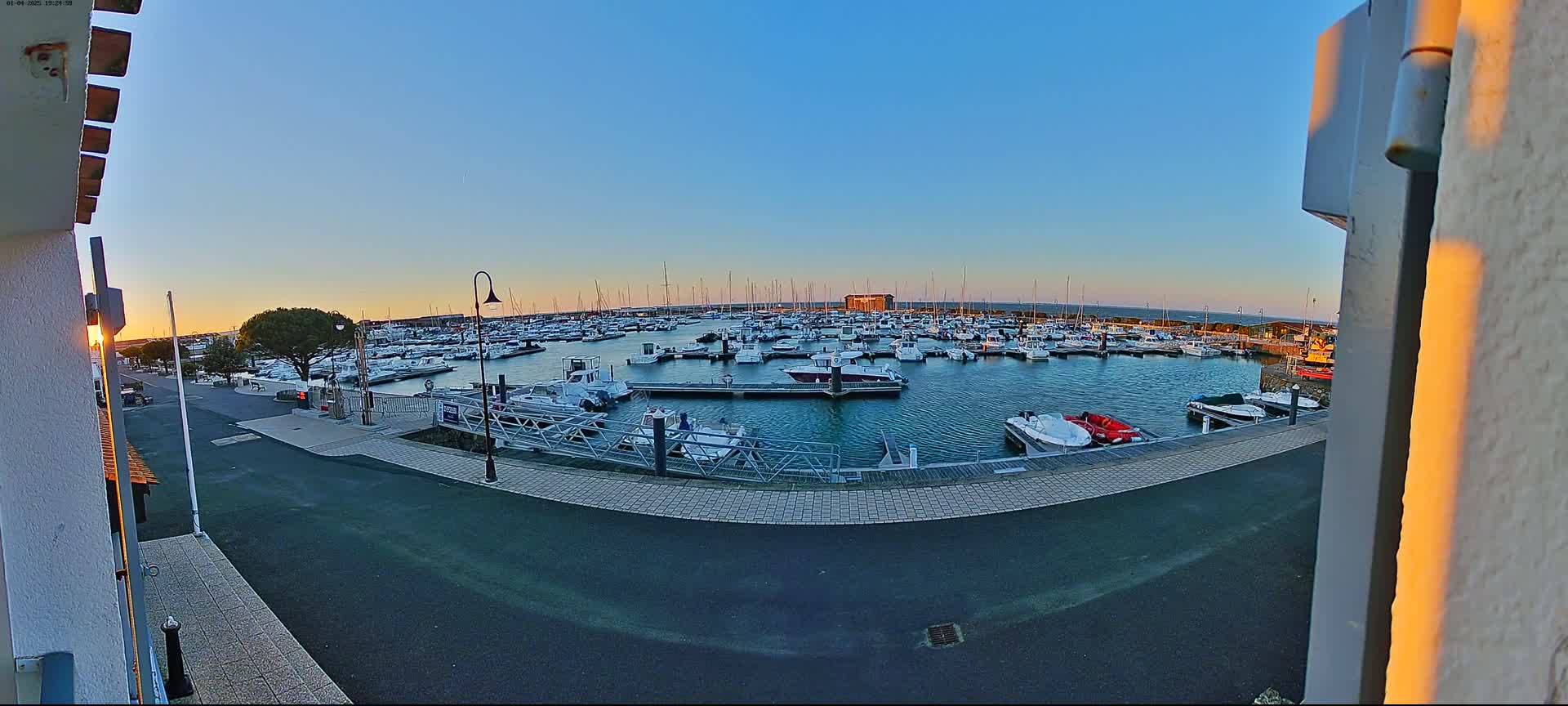 A marina filled with numerous boats is seen at sunset under a clear sky.
