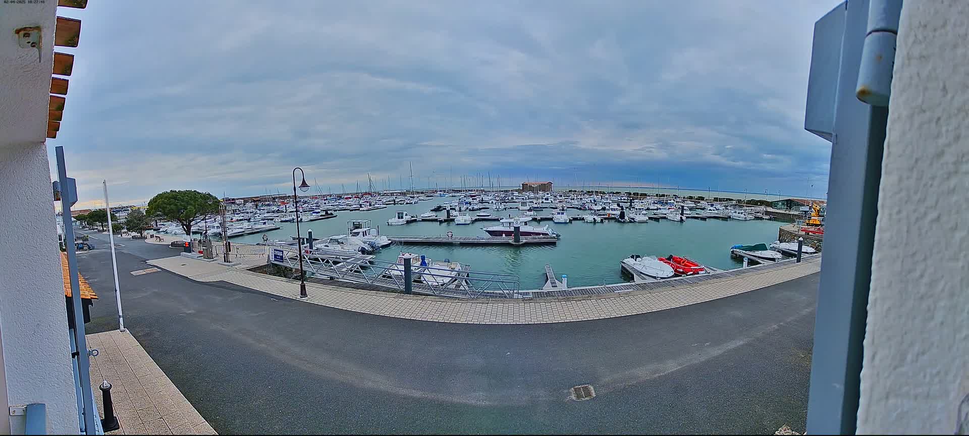 A marina filled with numerous boats is seen under a cloudy sky.