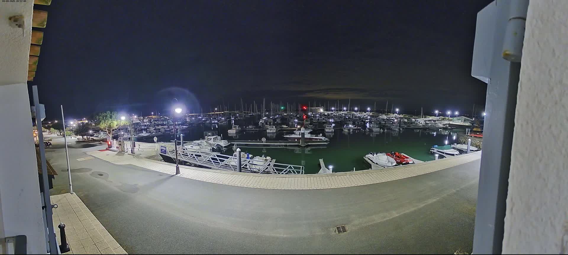 A marina filled with numerous boats is visible at night under a dark sky.