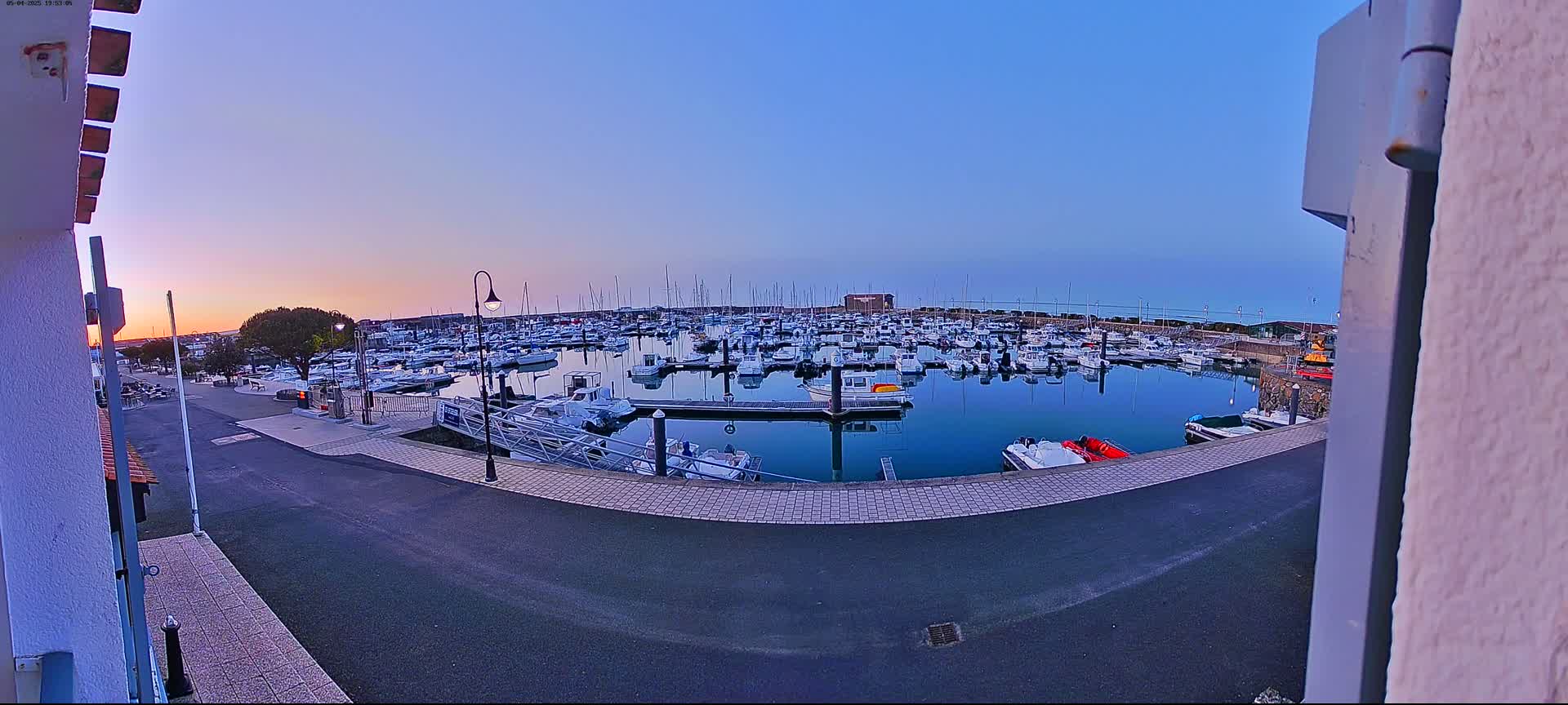 A calm marina filled with numerous boats at sunset under a clear, twilight sky.