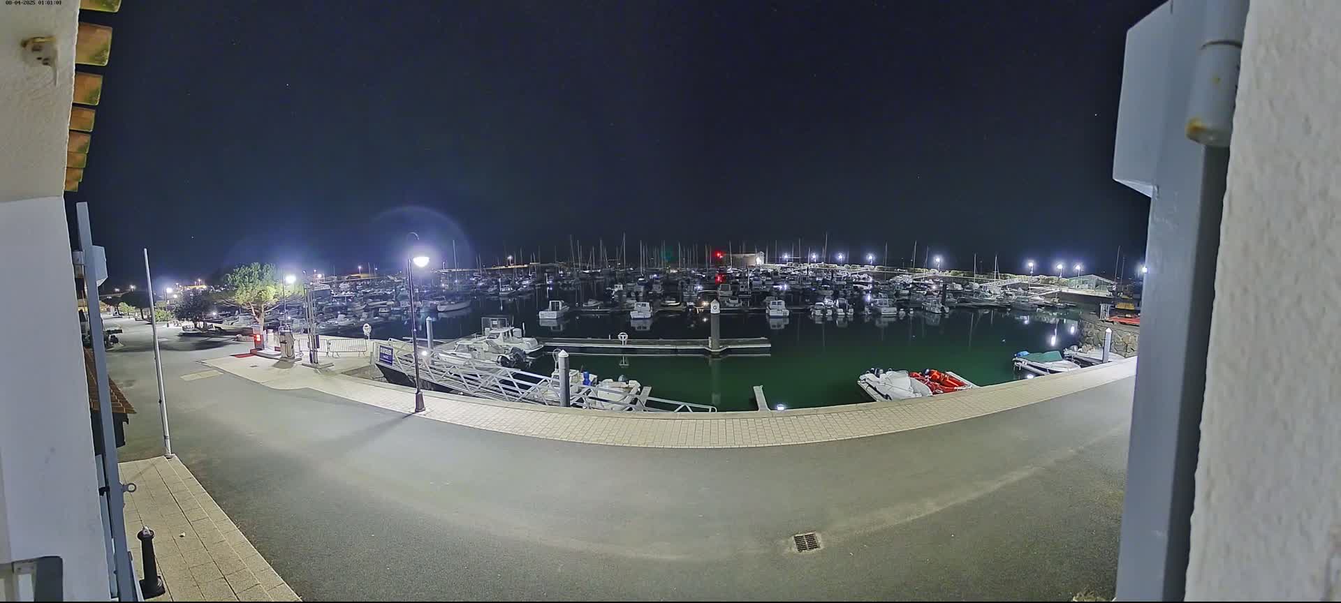 A nighttime view of a marina filled with boats, under a clear, dark sky.