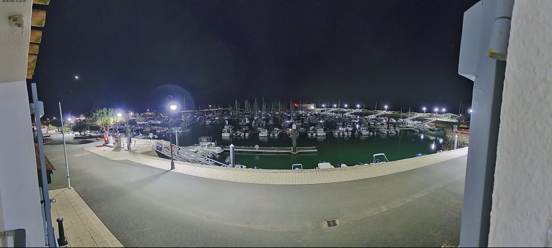 A nighttime view of a marina filled with numerous boats under a clear, starry sky.