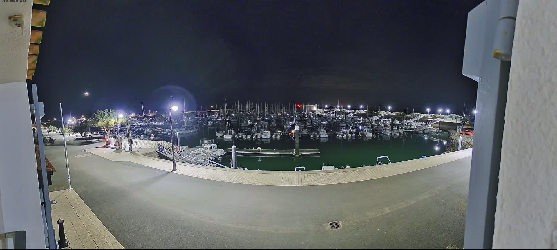 A nighttime view of a marina filled with many boats under a clear, dark sky.