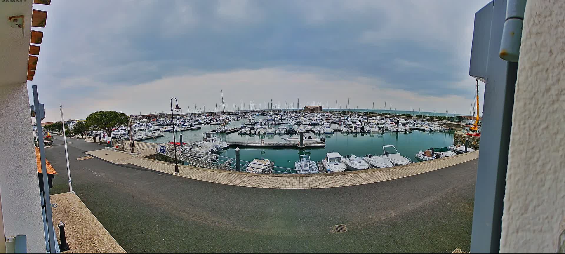 A marina filled with numerous boats is seen under an overcast sky.