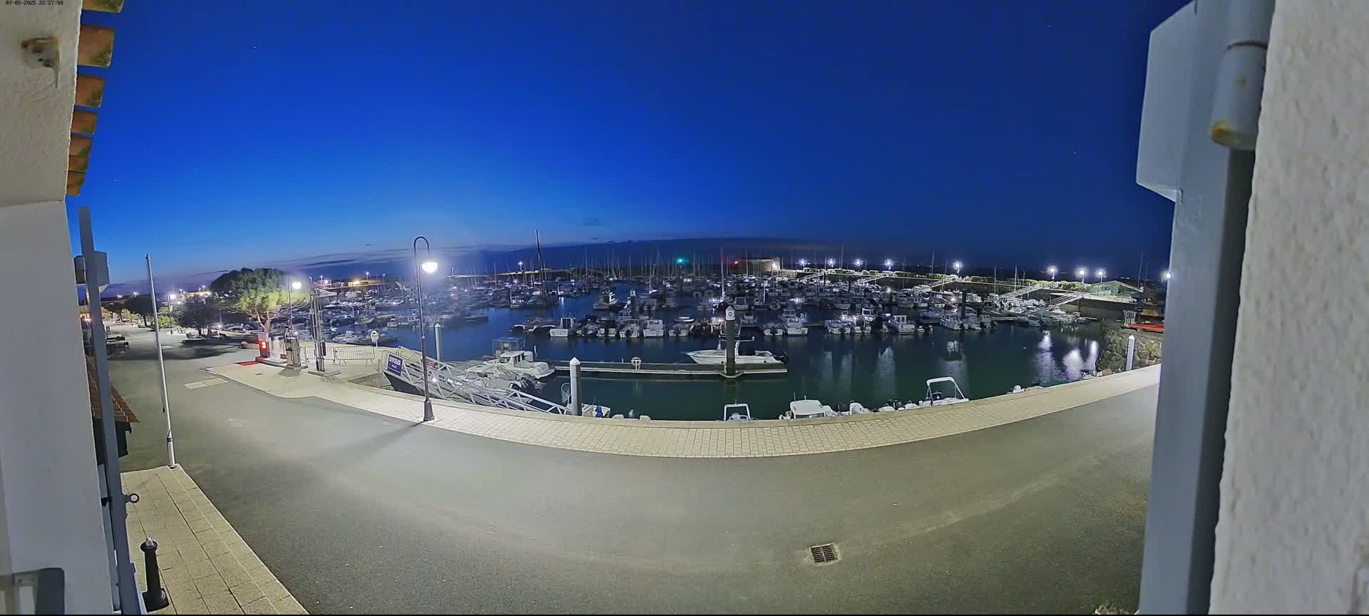 A marina filled with numerous boats is visible at night under a clear, dark blue sky.