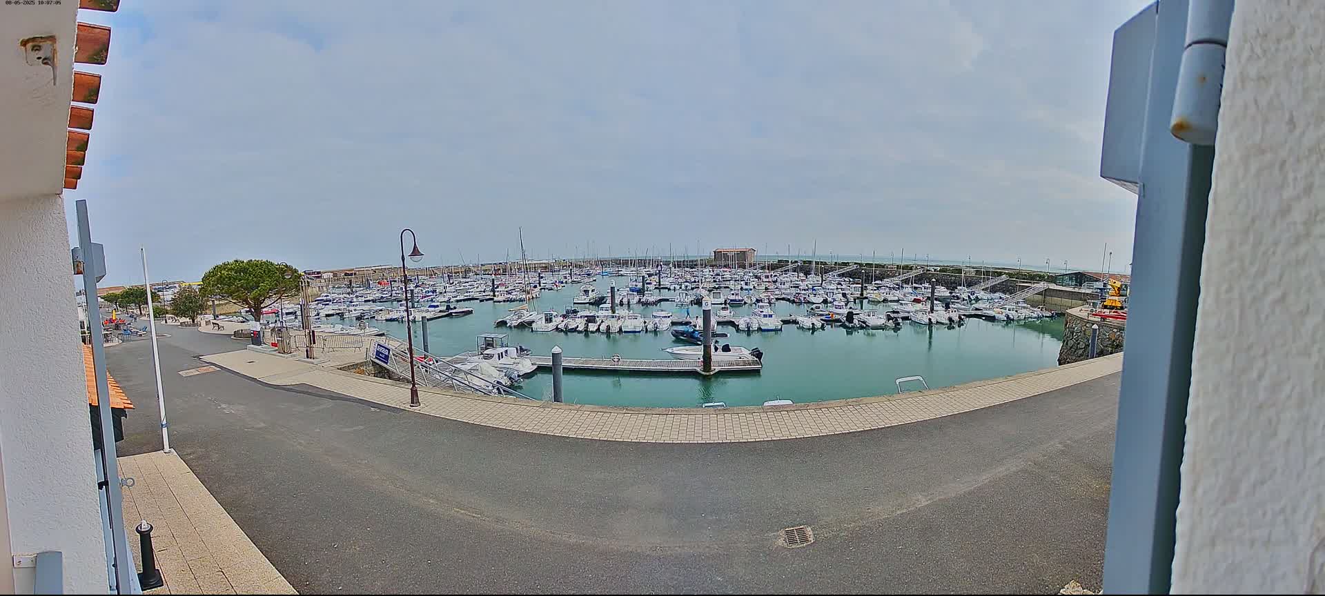 A marina filled with numerous boats is seen under a mostly cloudy sky.
