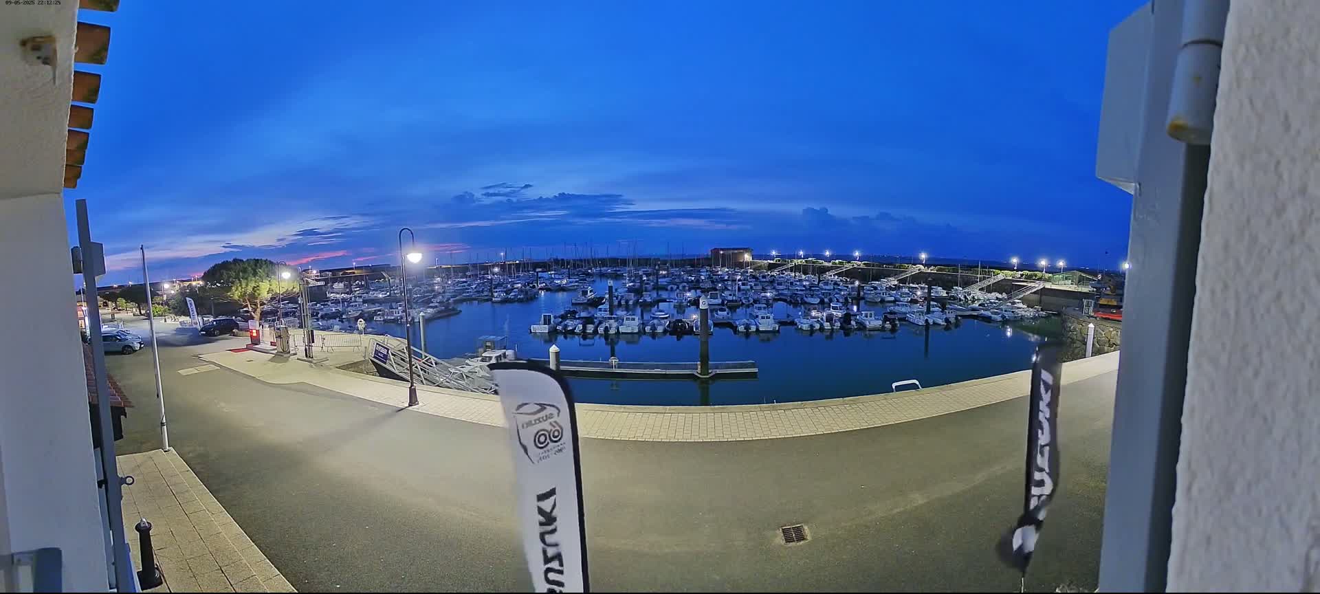 A marina filled with boats is seen at twilight under a clear, dark blue sky.