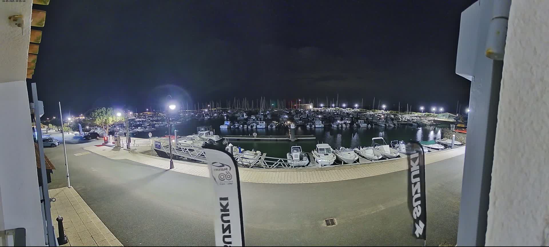 At night, a marina filled with numerous boats is illuminated under a dark sky.