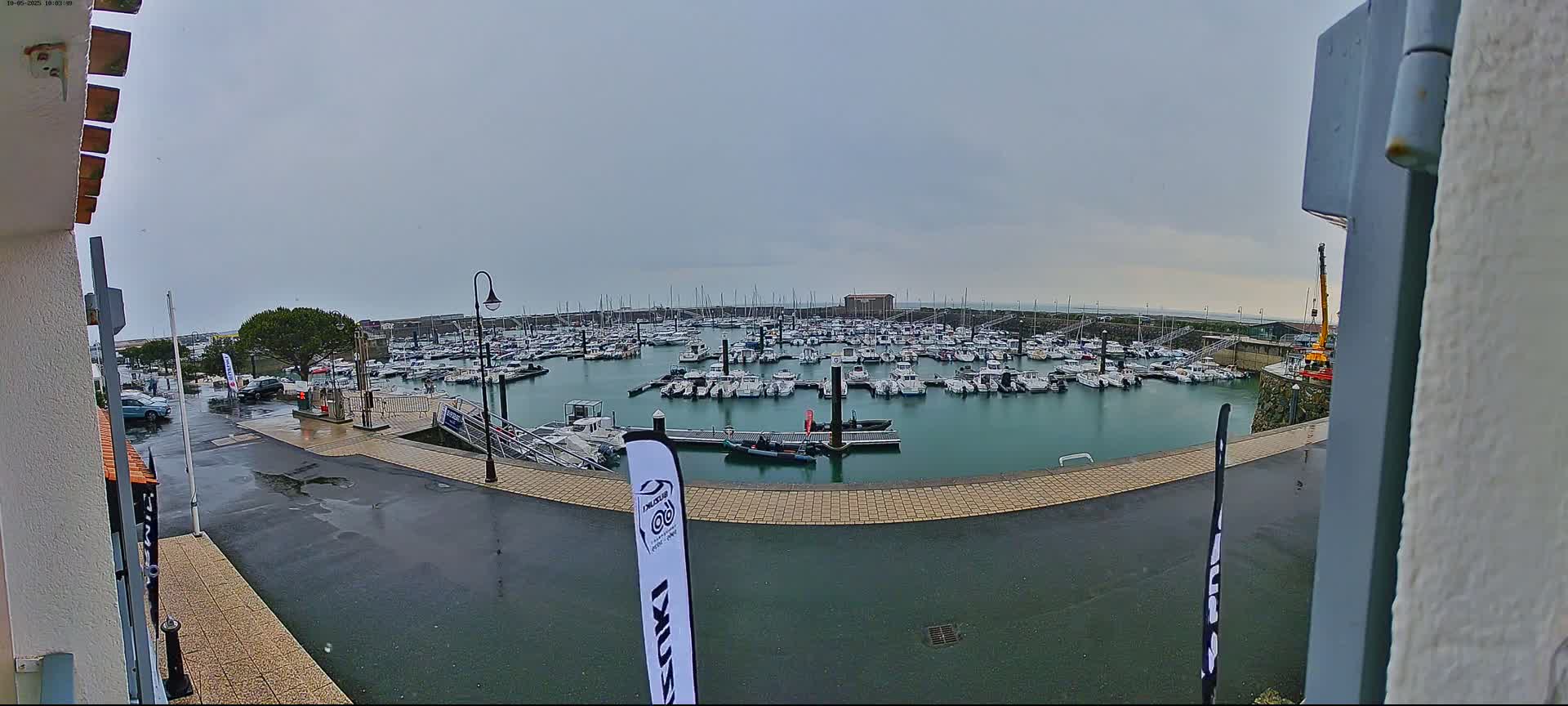 A wet, overcast day at a marina filled with numerous boats.
