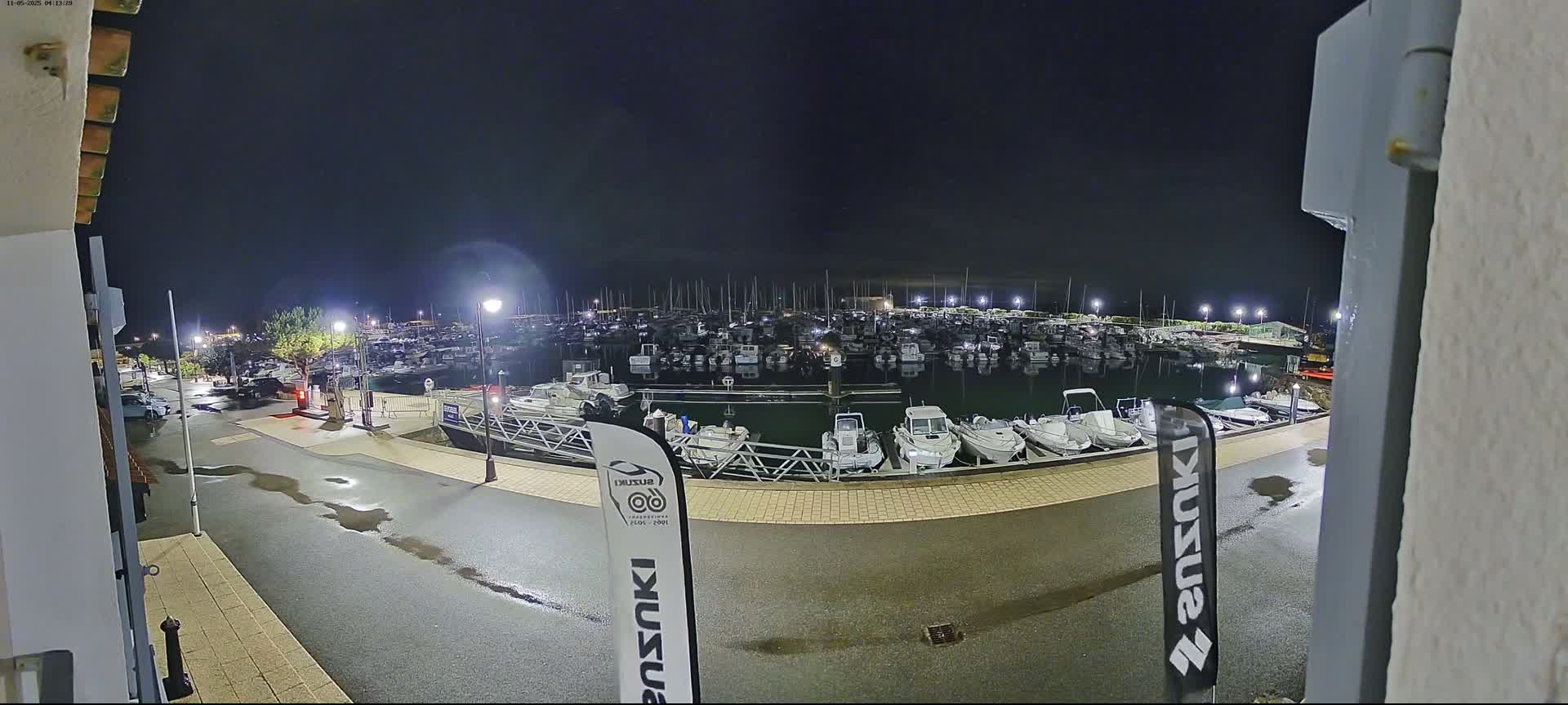 A wet nighttime marina is filled with many docked boats under a dark sky.