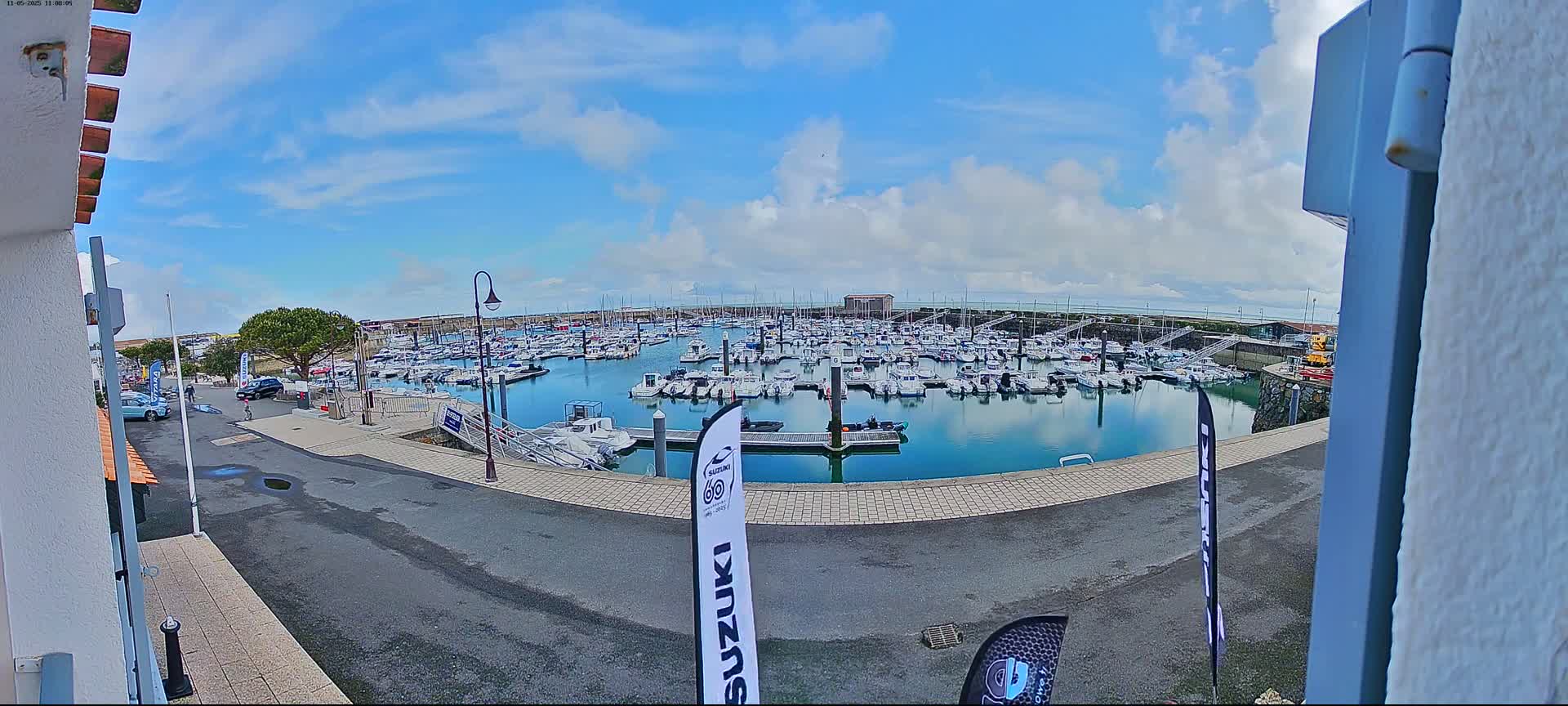 A marina filled with numerous boats is seen on a partly sunny day with some clouds.