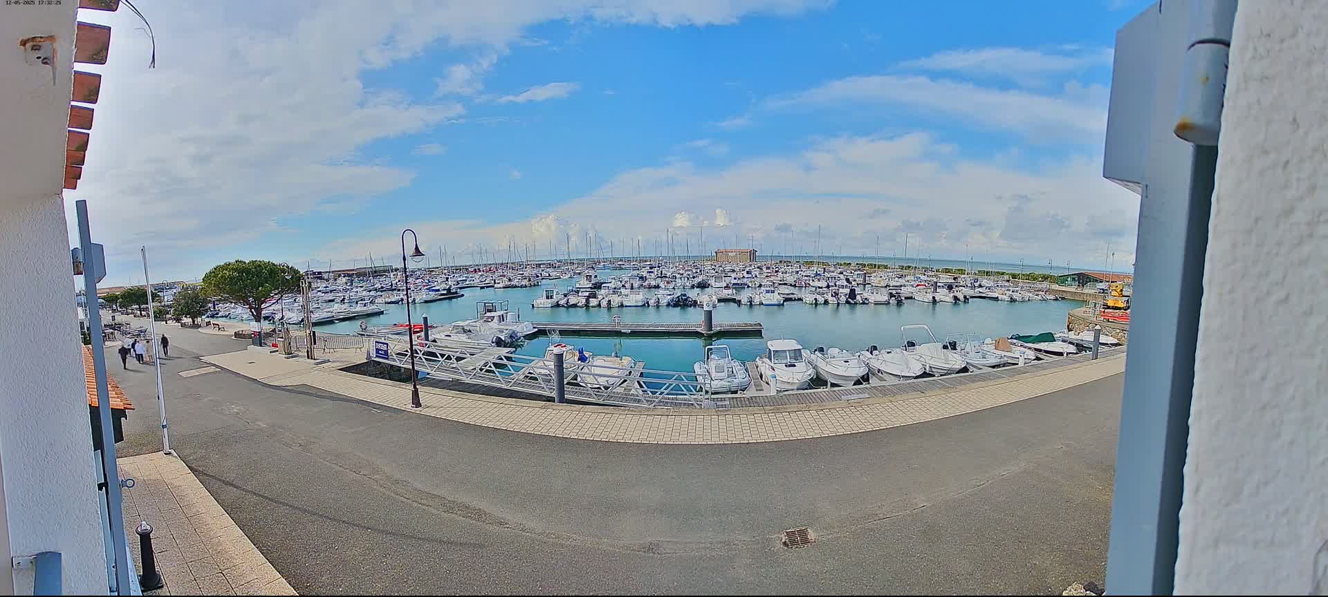 A marina filled with numerous boats under a partly cloudy sky.