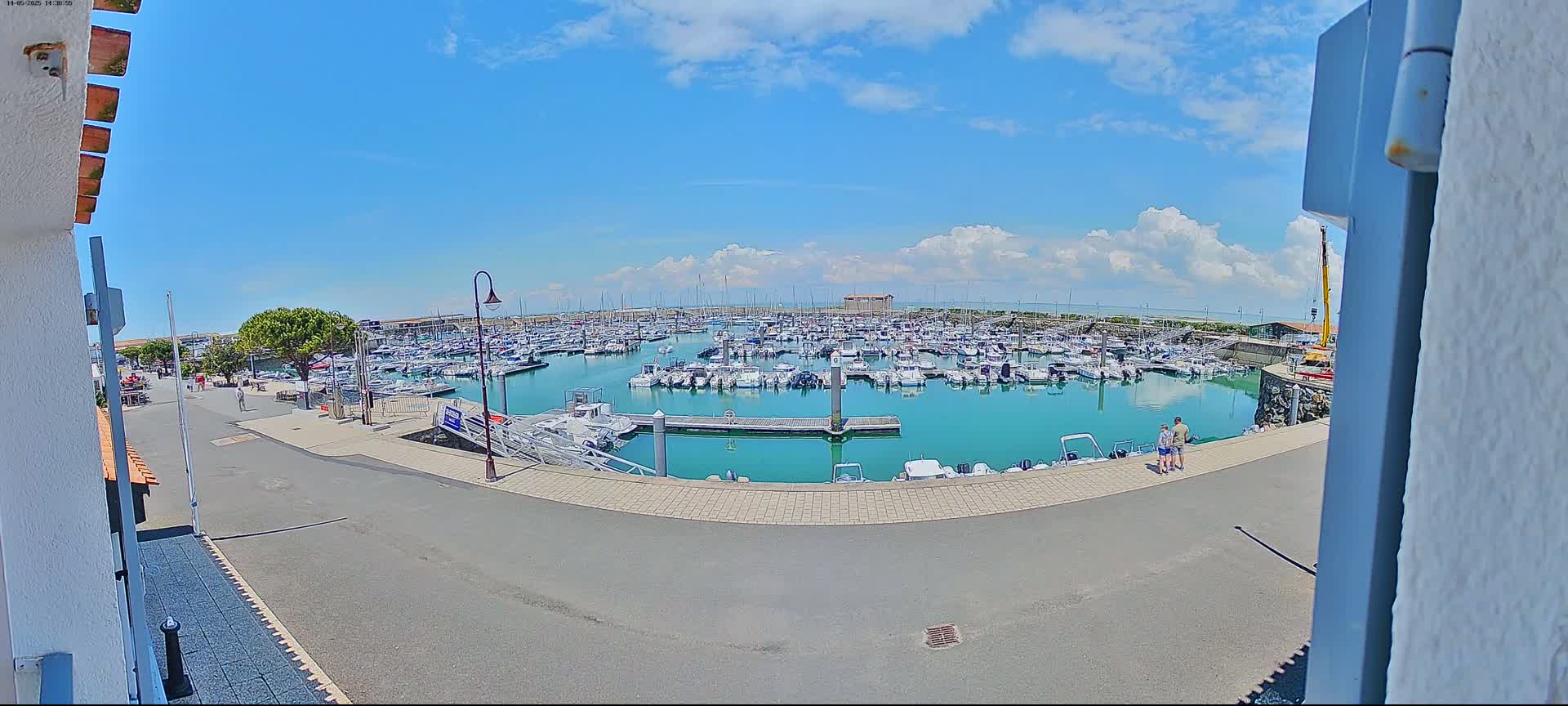 A marina filled with numerous boats is seen under a partly cloudy sky.
