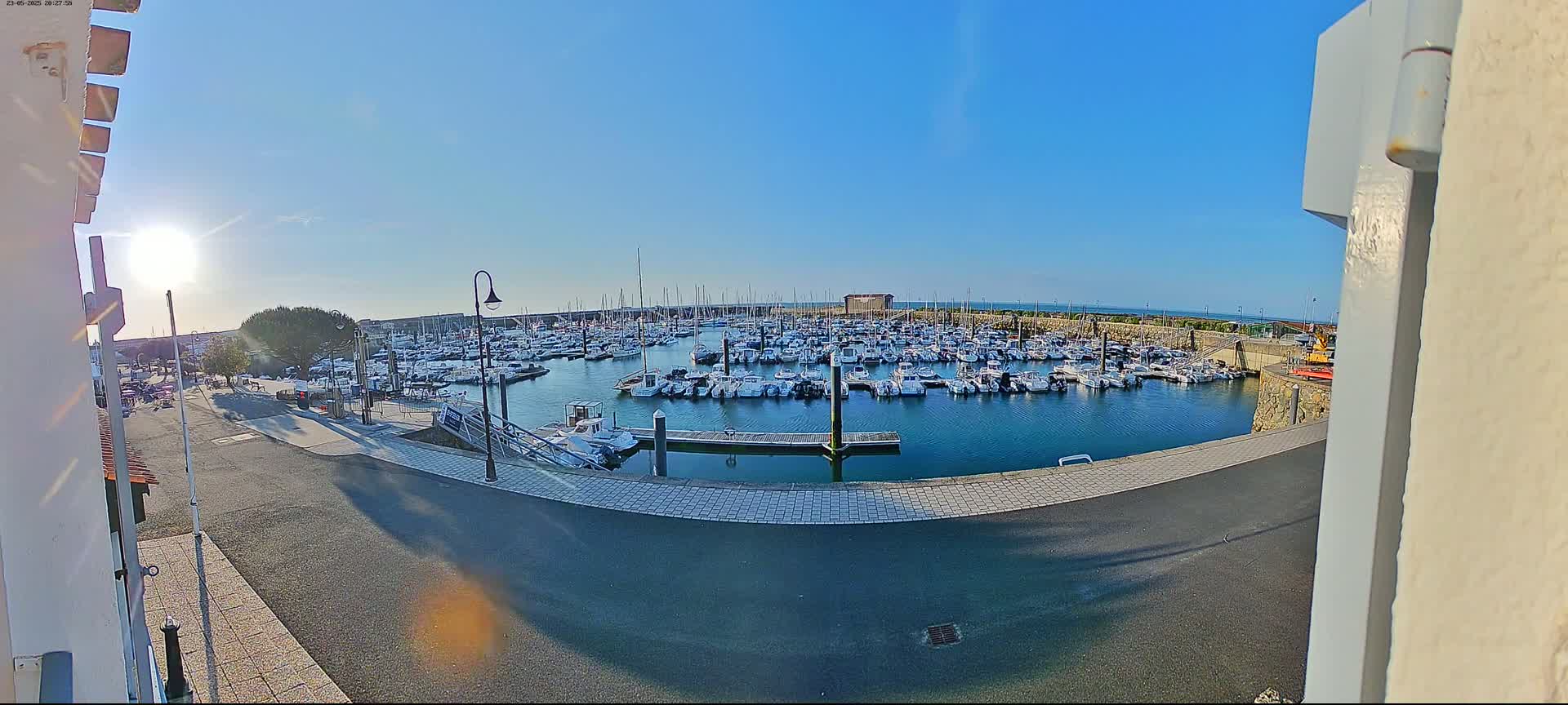 A sunny day shows a harbor filled with many boats and yachts, viewed from a slightly elevated position.