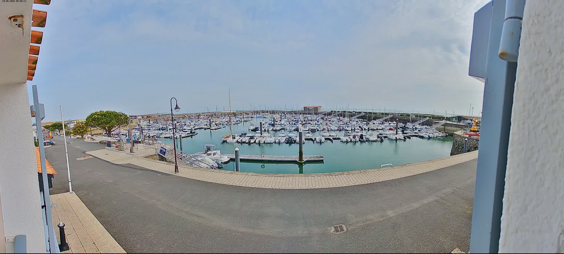 A marina filled with numerous boats is seen on a partly cloudy day.