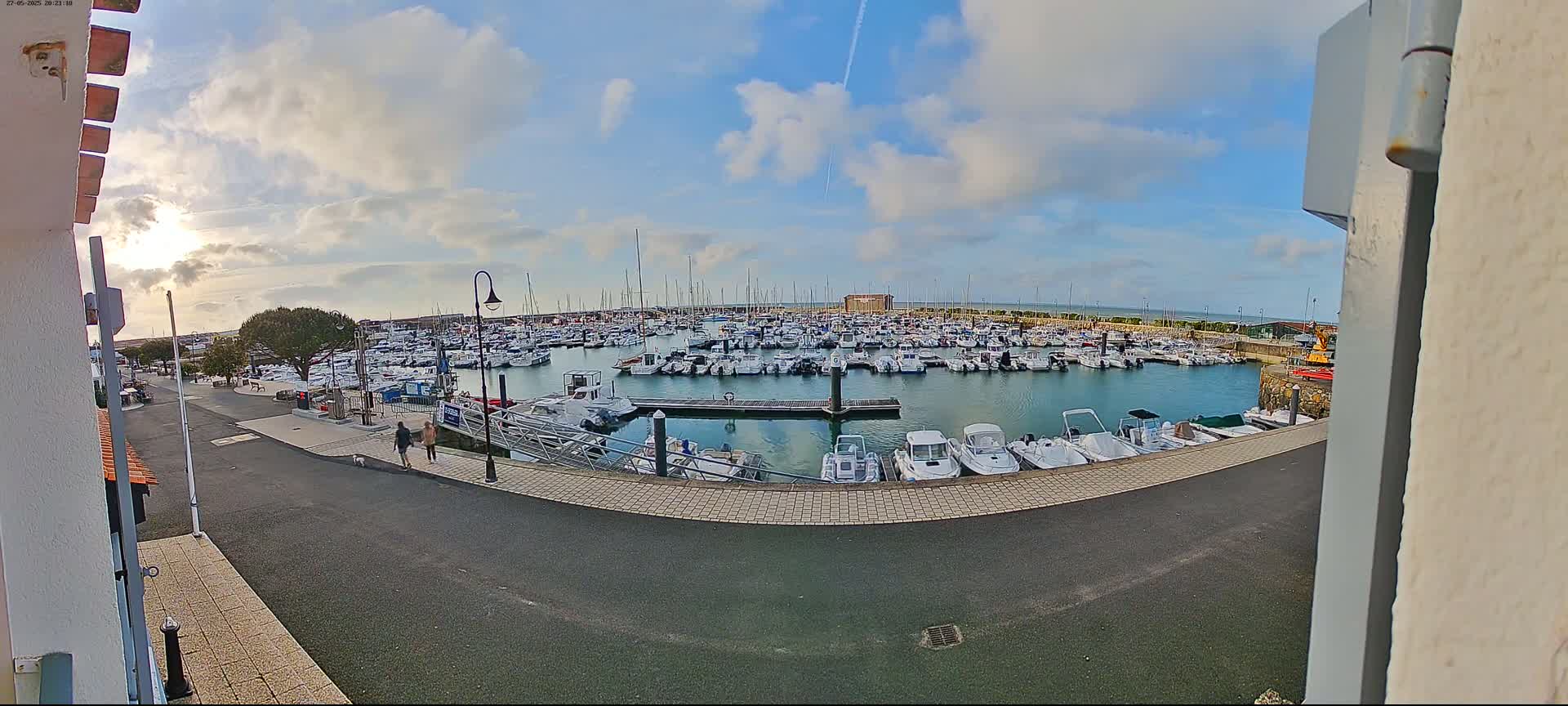 A marina filled with numerous boats is seen on a partly sunny day with some clouds in the sky.