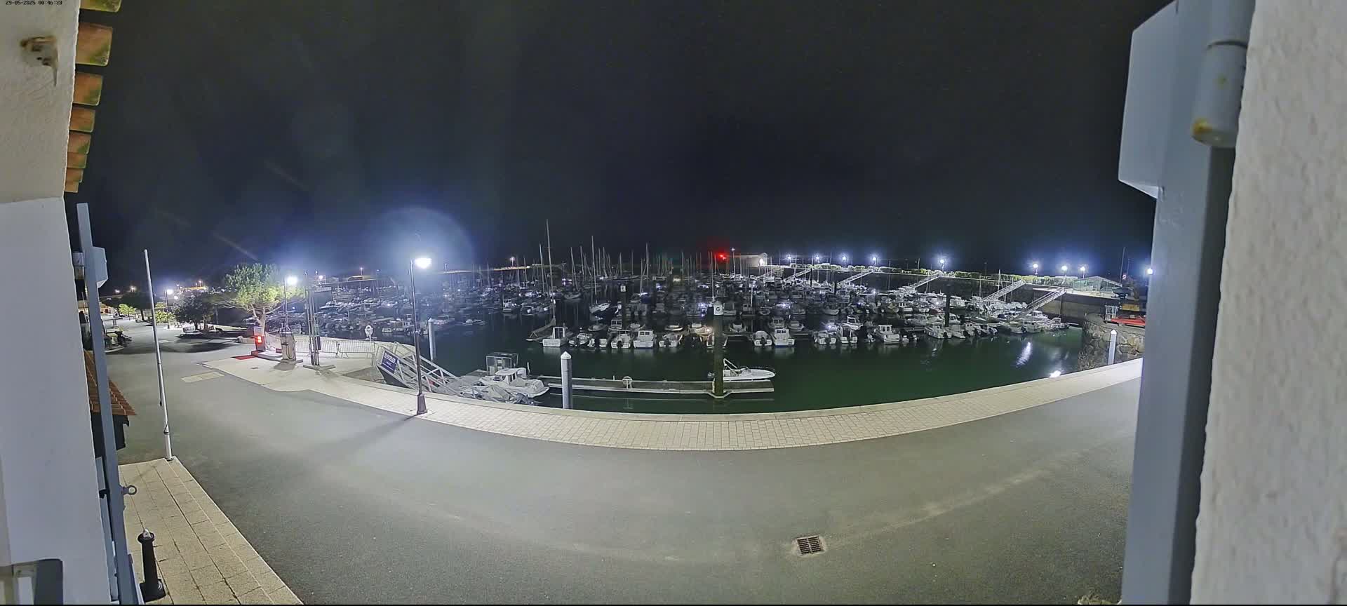 A marina filled with numerous boats is seen at night under clear skies, as viewed from an elevated position.