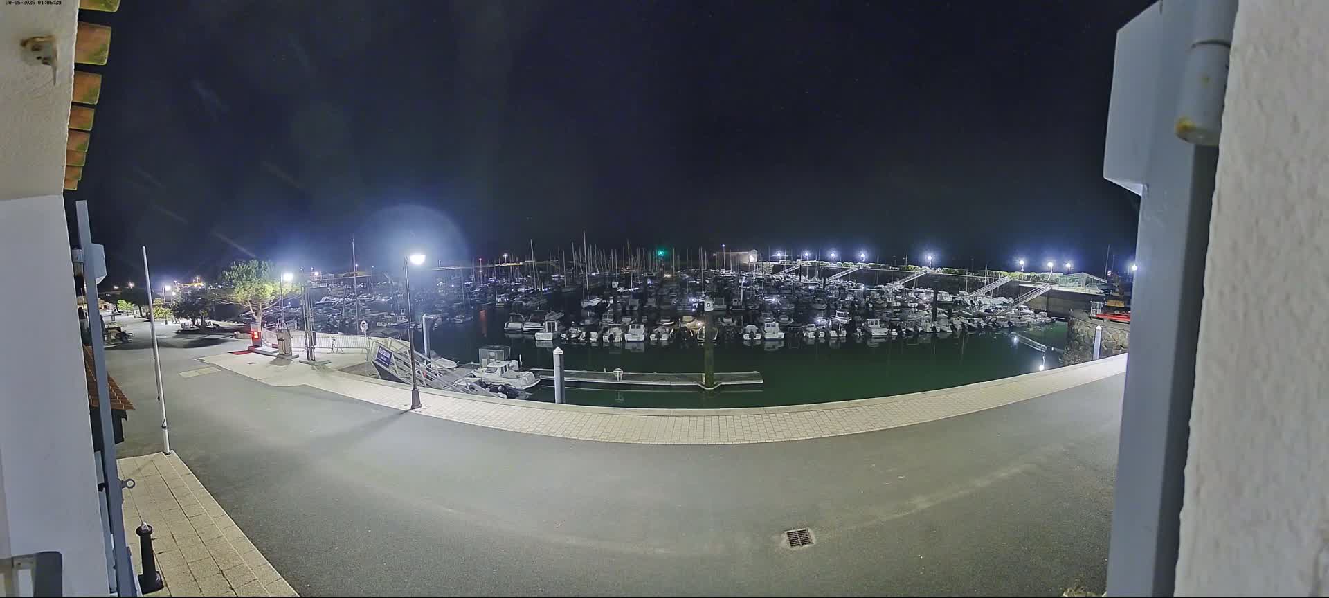 A nighttime view of a marina filled with numerous boats under a clear, dark sky.