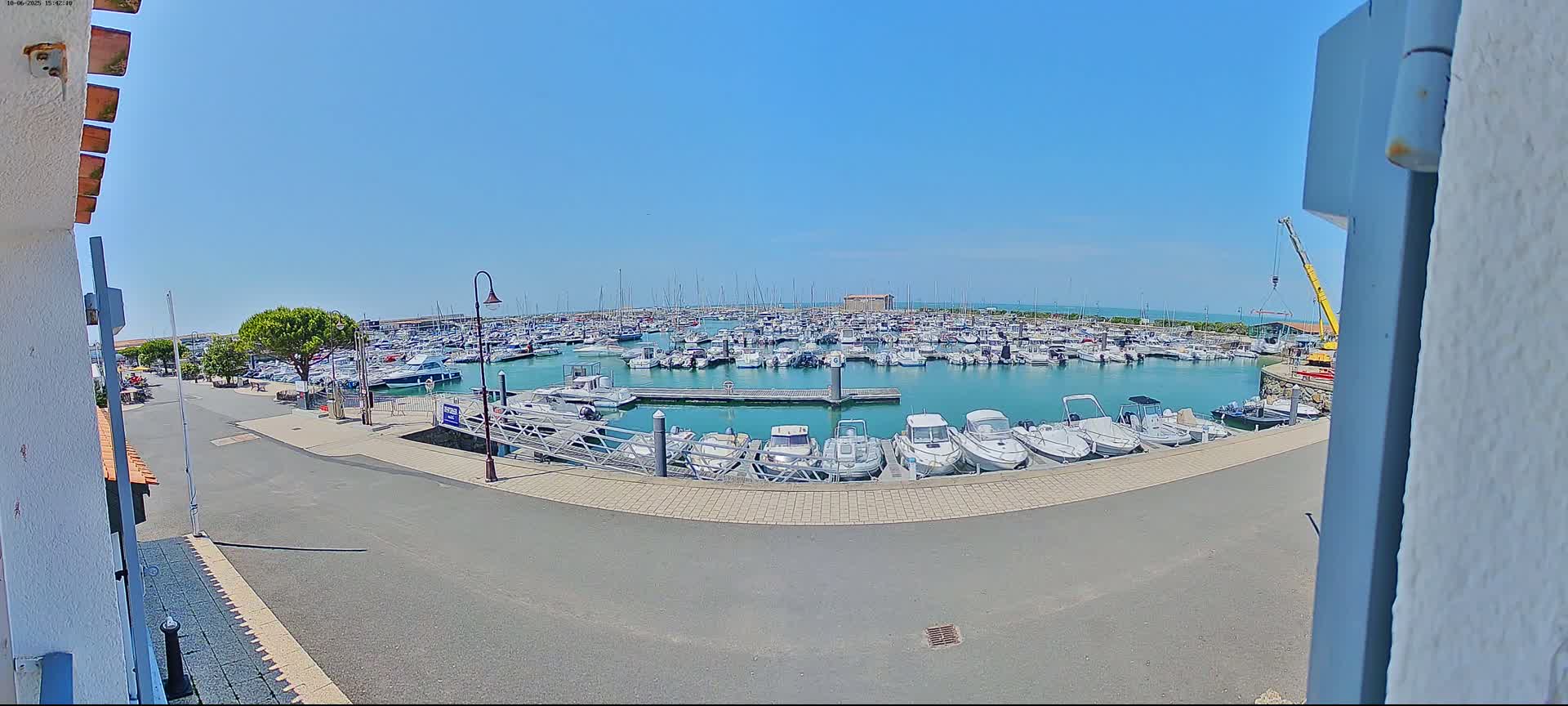 A marina filled with numerous boats is viewed from a slightly elevated position on a sunny day.