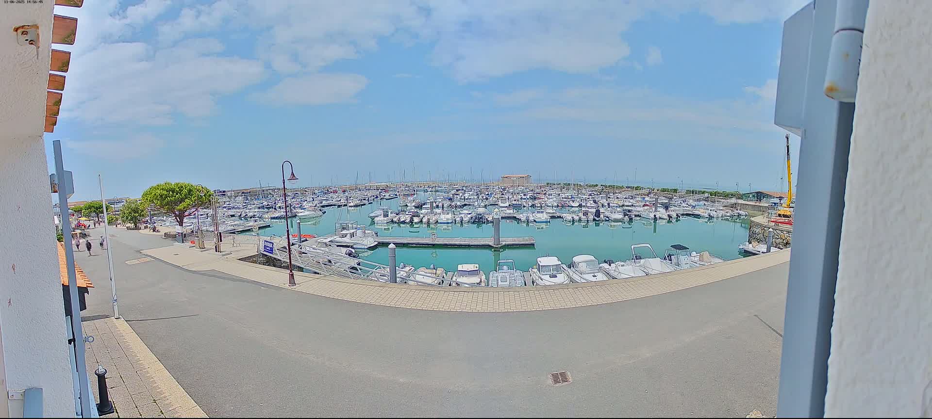 A marina filled with numerous boats is seen on a partly sunny day.