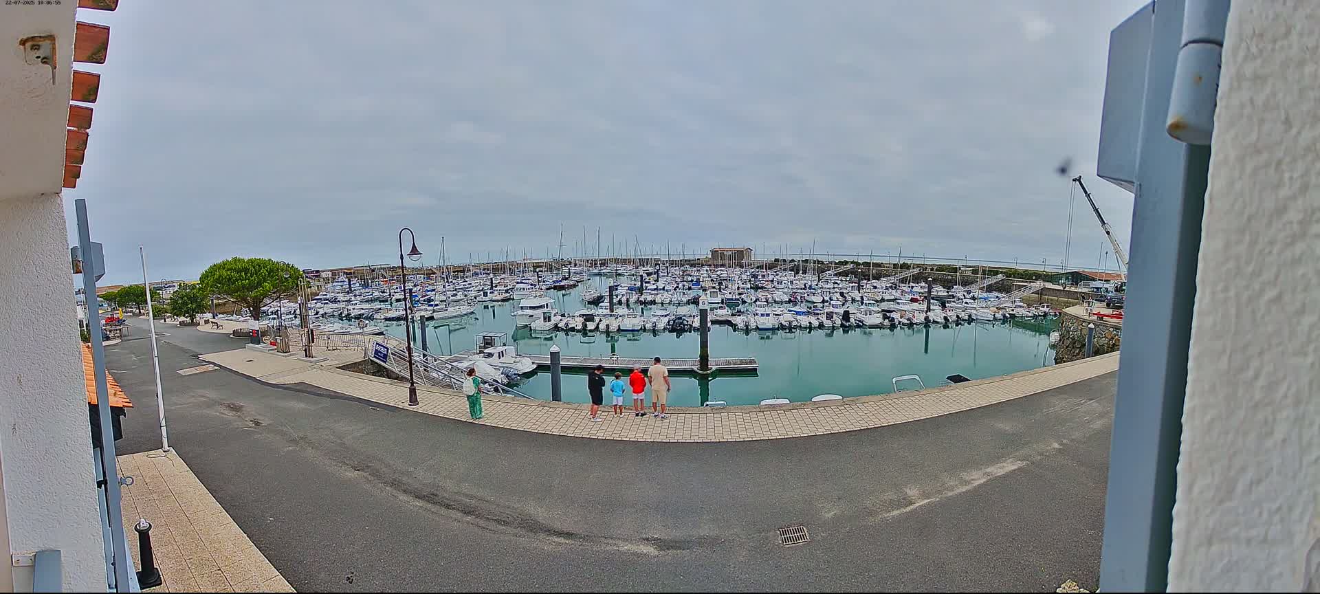 A family stands near a marina filled with numerous boats on an overcast day.