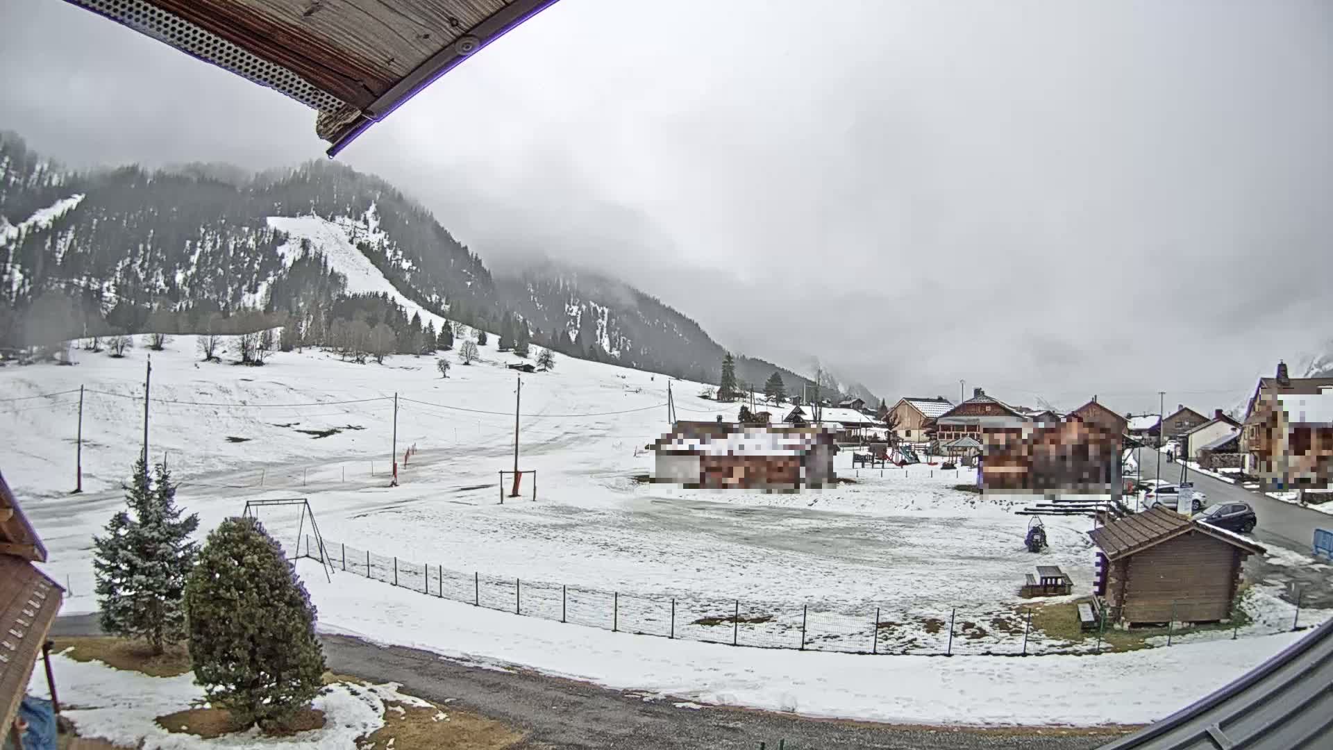 A snow-covered village nestled in a valley surrounded by overcast mountains.