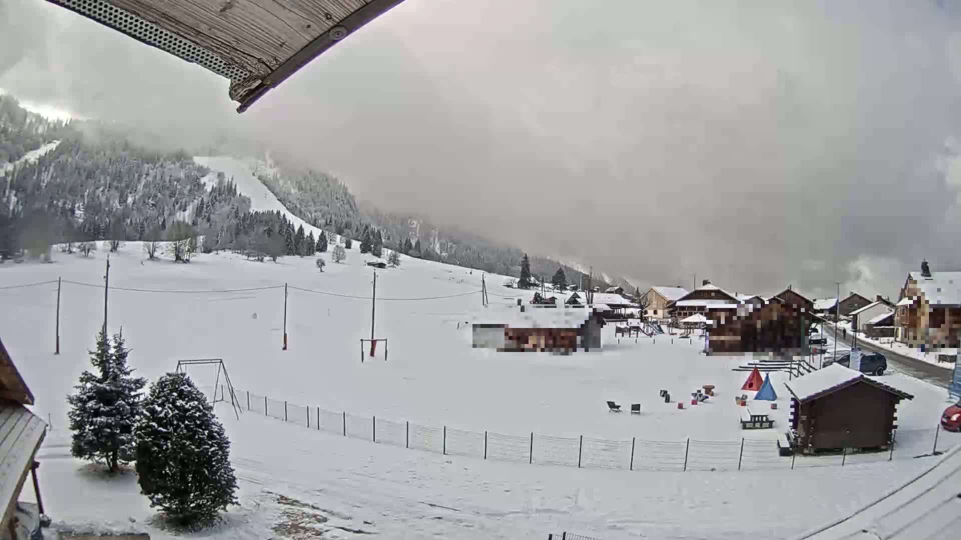 A snow-covered village nestled in a mountainous region under an overcast sky.