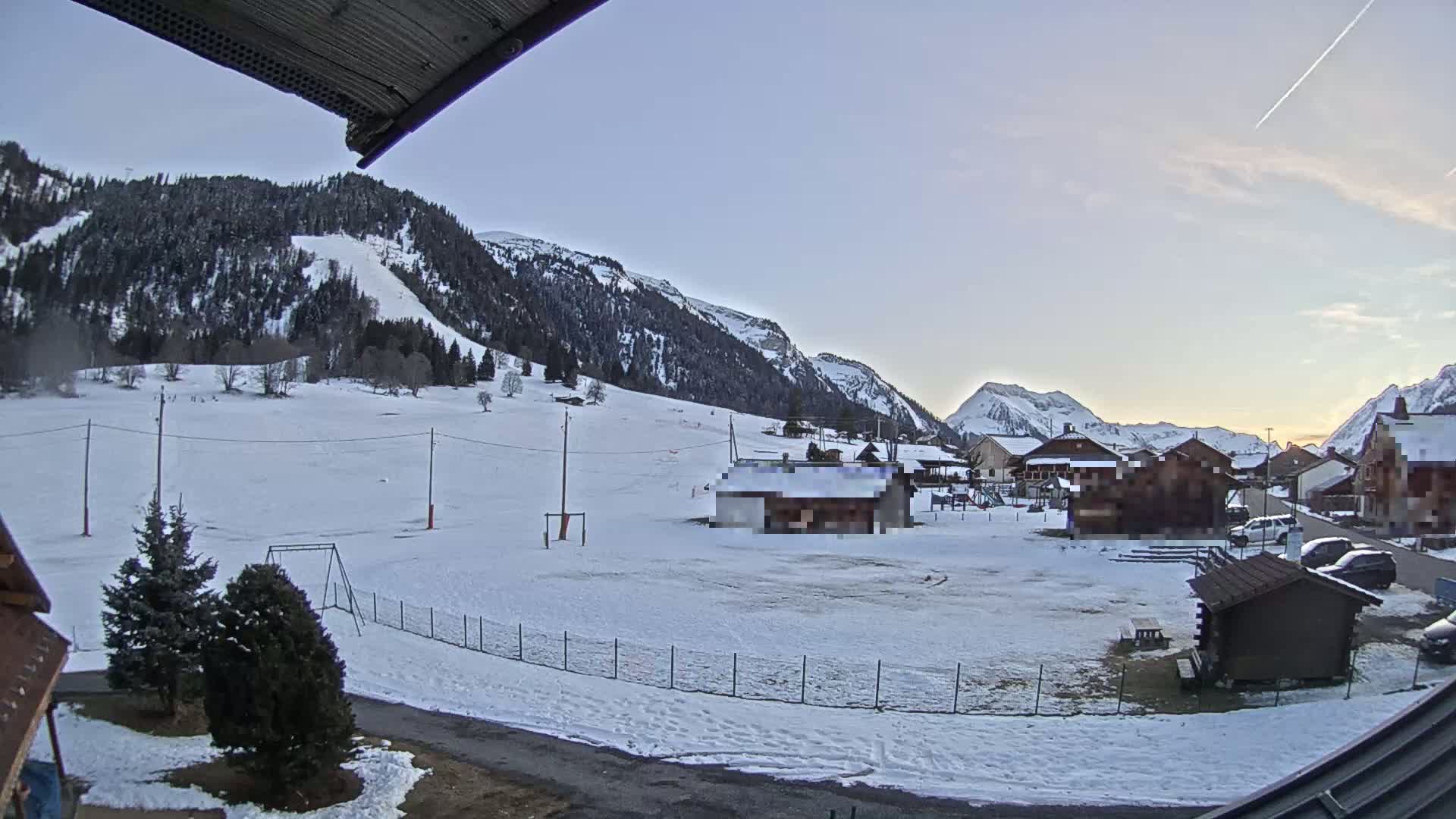 A snow-covered village nestled in a valley between mountains under a clear, twilight sky.