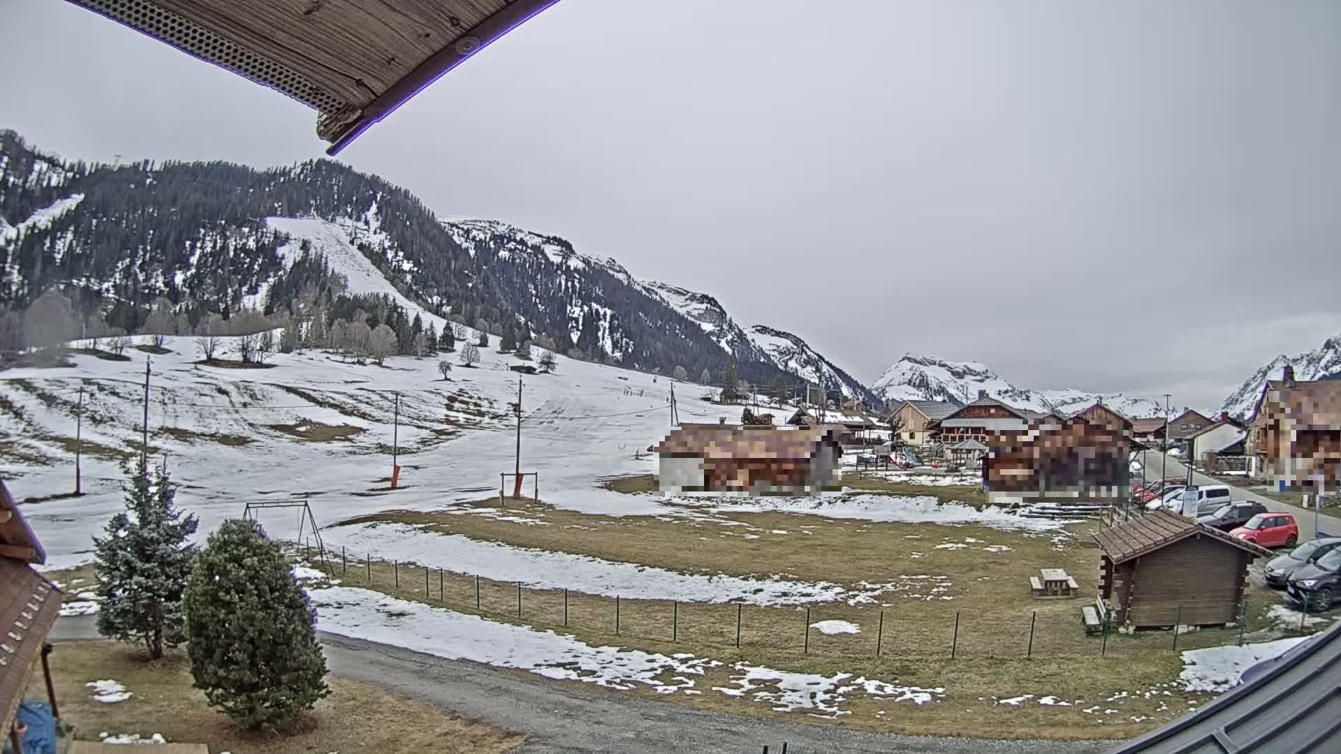 A snow-dusted village nestled in a valley between mountains under an overcast sky.