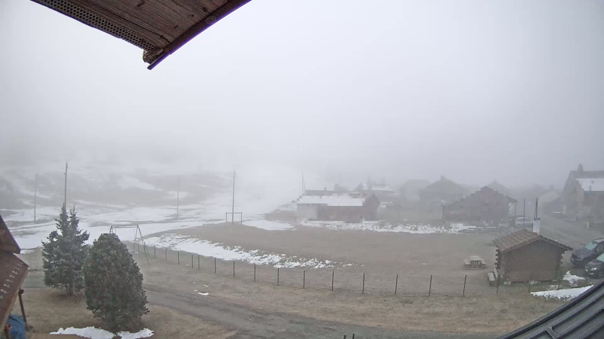A foggy, snowy landscape with several small buildings and a playground is visible from a high vantage point.