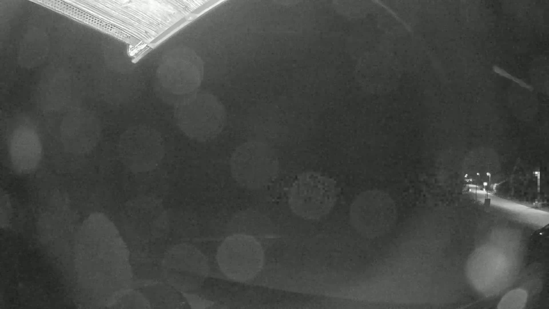 A nighttime, rain-blurred view from inside a vehicle shows a dimly lit road ahead.