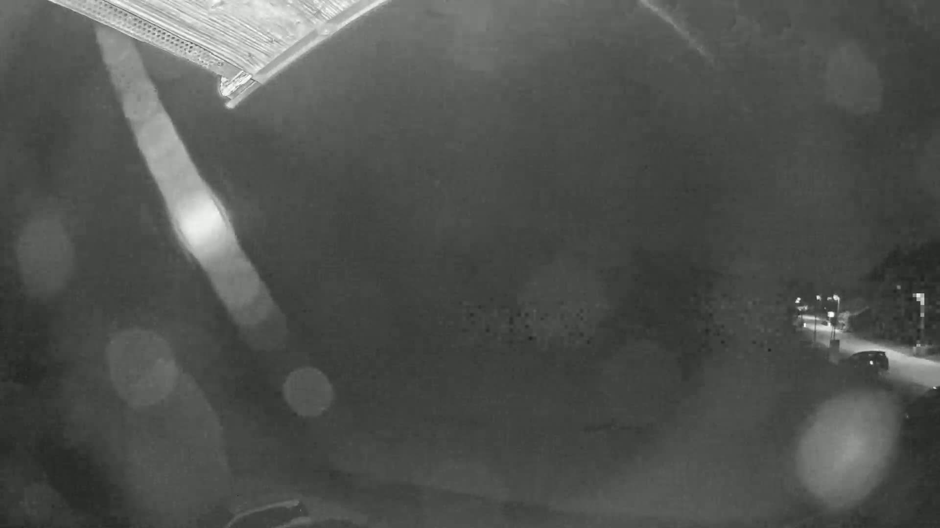 A nighttime, blurry view of a road with some cars visible, possibly snowing or raining.