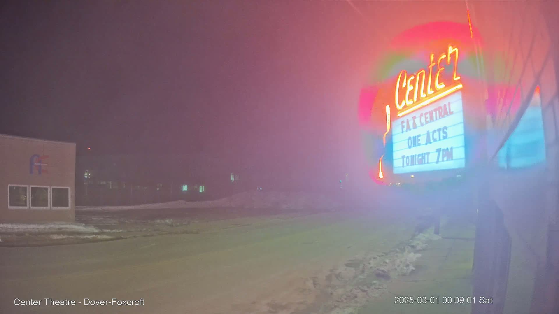 A nighttime, foggy scene shows a theater marquee advertising "One Acts" at 7 PM, with a building visible in the background.