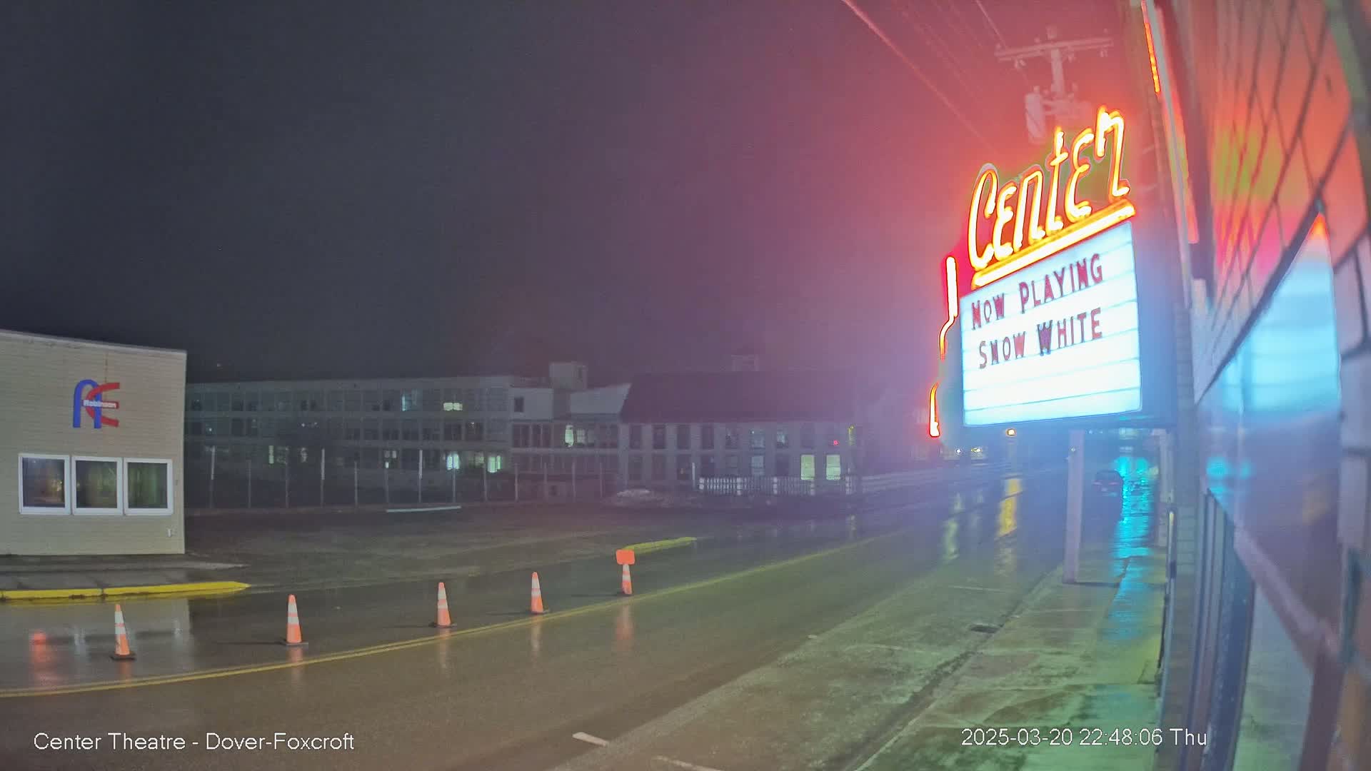 A rain-slicked street at night shows a movie theater marquee advertising "Snow White."