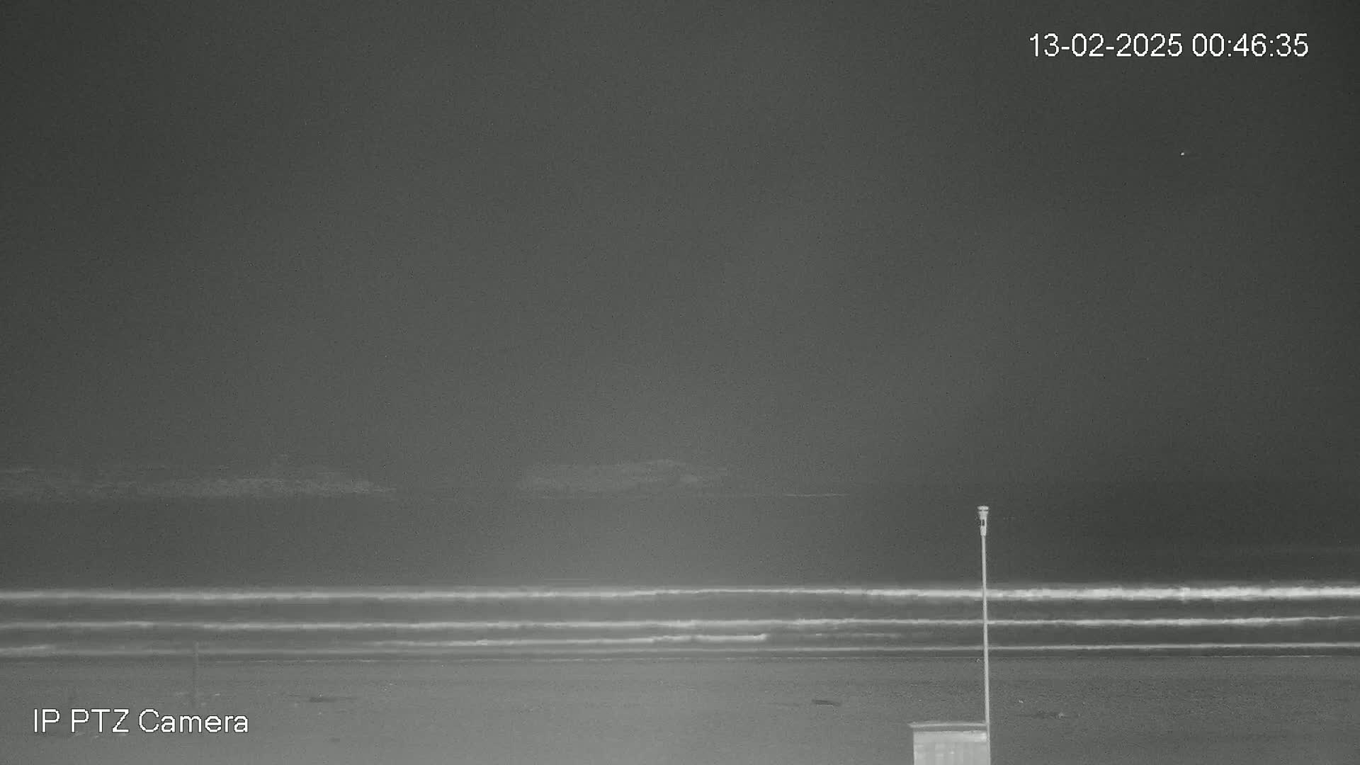 A nighttime beach scene shows gently rolling waves under a dark sky.