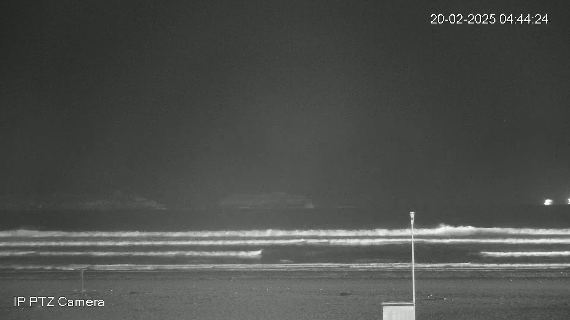 Under a dark night sky, waves roll onto a sandy beach.