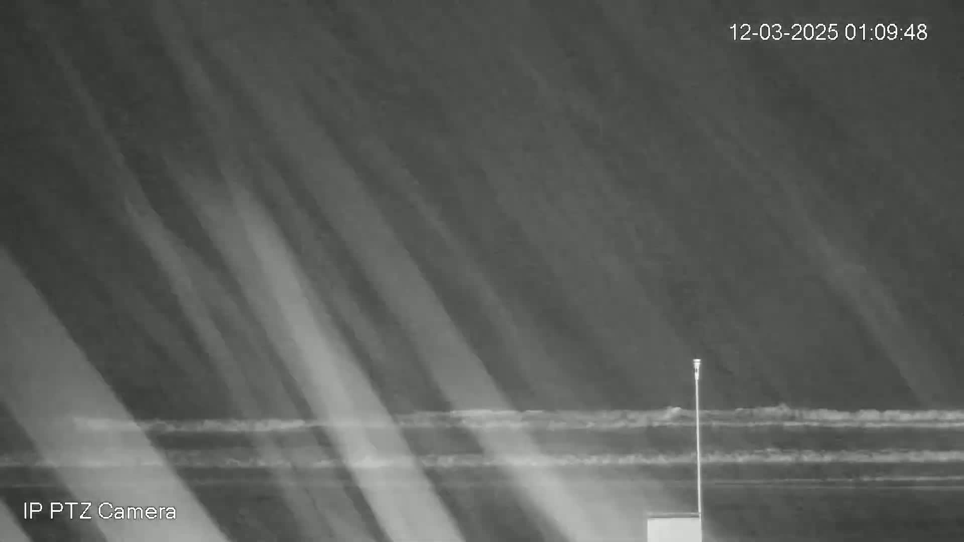 A nighttime, low-light image shows dark, wavy water under a dark sky with diagonal streaks of light.