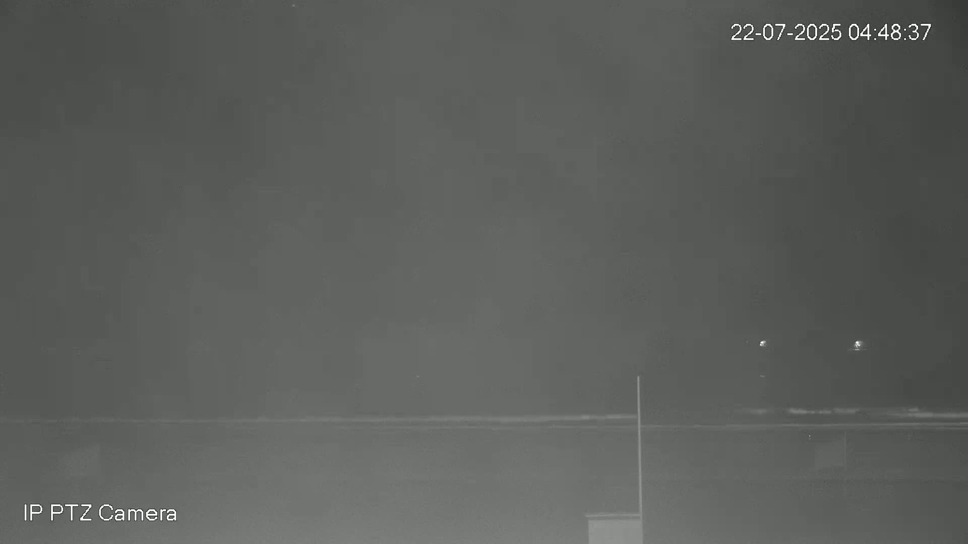 A nighttime, low-light view shows a dark, seemingly calm body of water under a hazy sky.