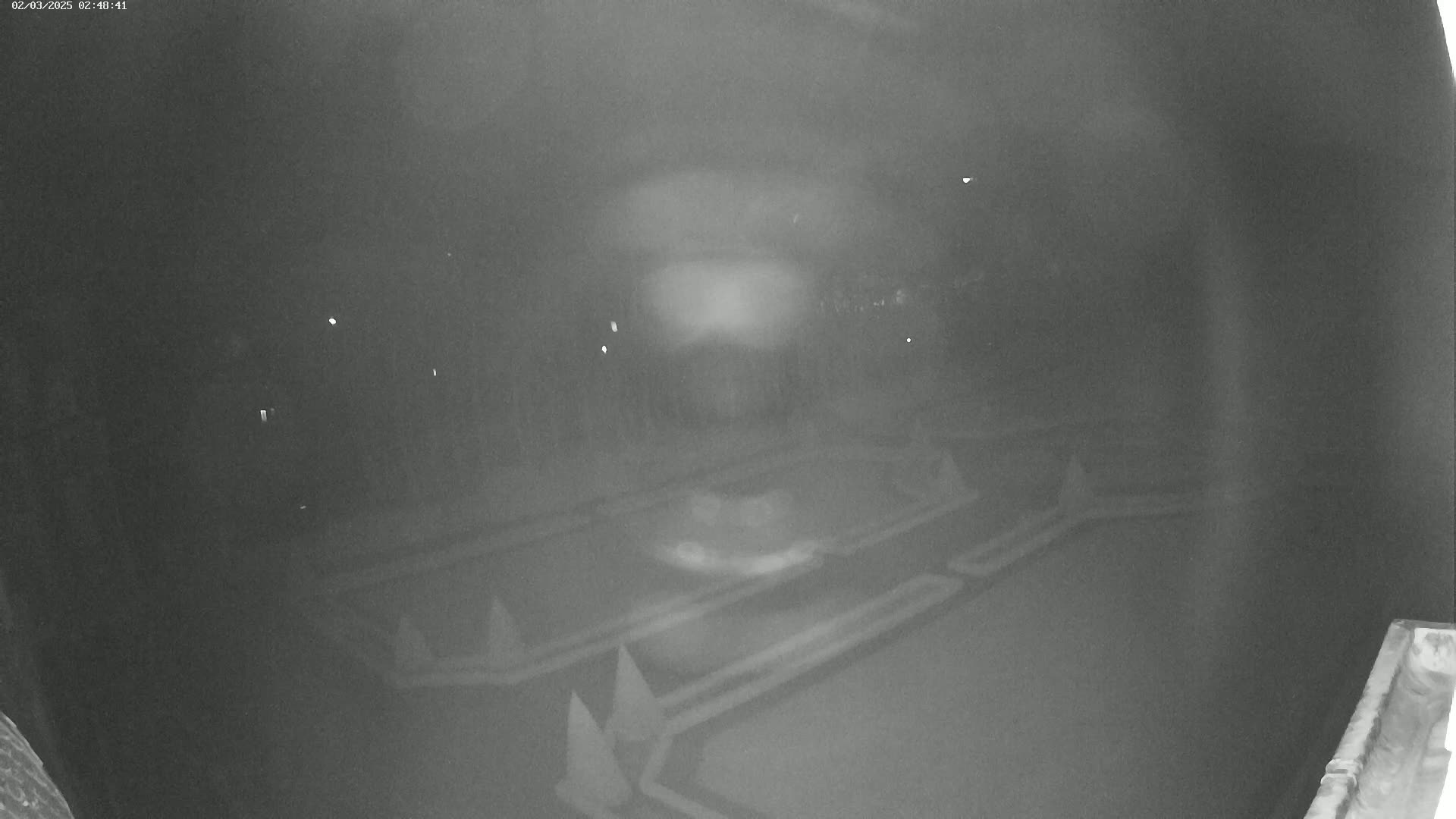 A nighttime, low-light image shows an outdoor area with a paved surface featuring several triangular markers, possibly for a game or course.