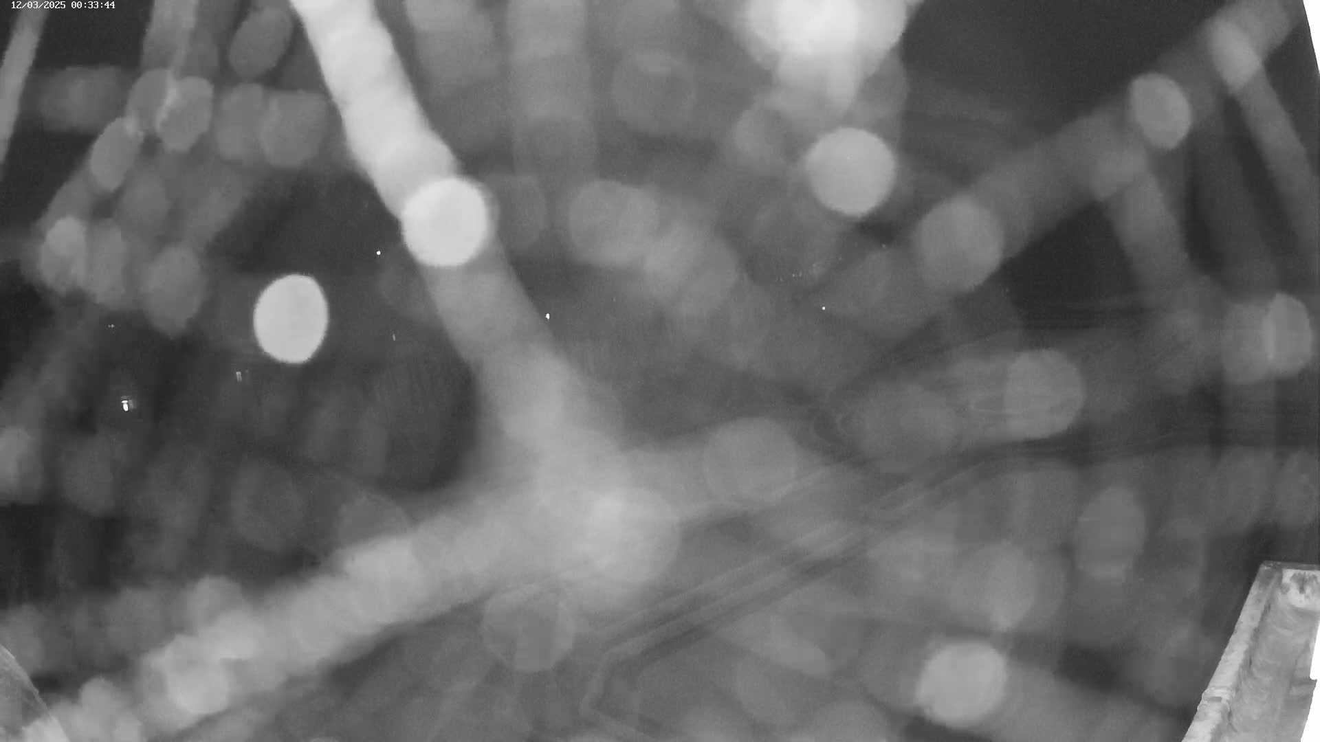 A blurry nighttime view shows out-of-focus lights and what appears to be rain or moisture on a lens.