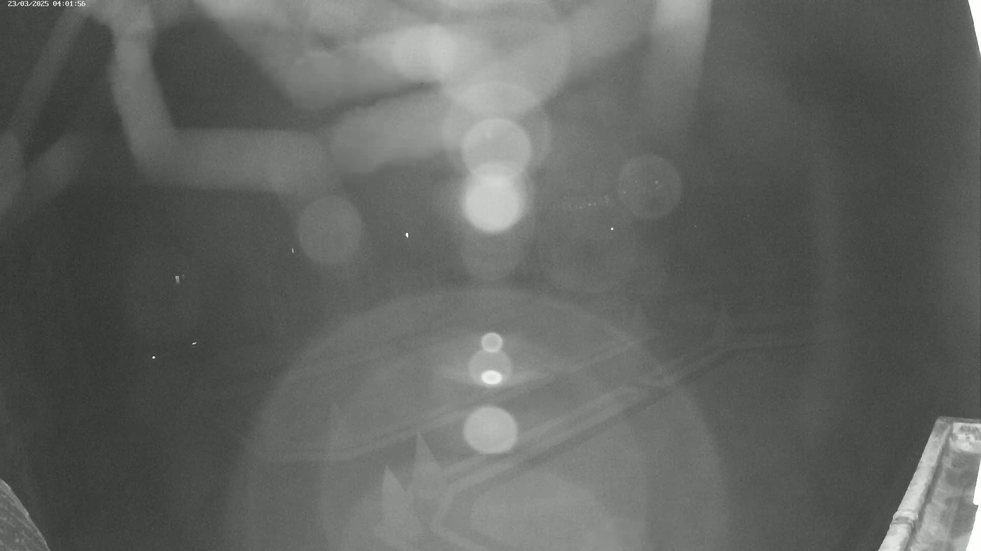 A blurry nighttime image shows out-of-focus lights and indistinct shapes on a dark surface.