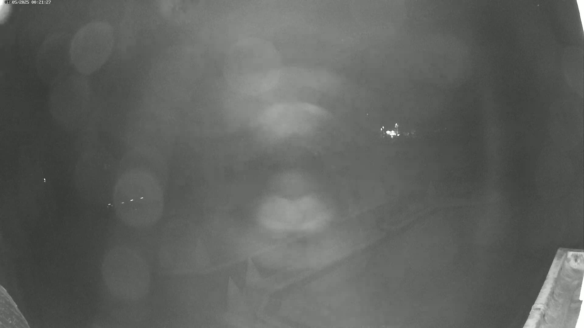 A blurry, nighttime image shows a hazy, indistinct view of a dark landscape with faint lights in the distance.
