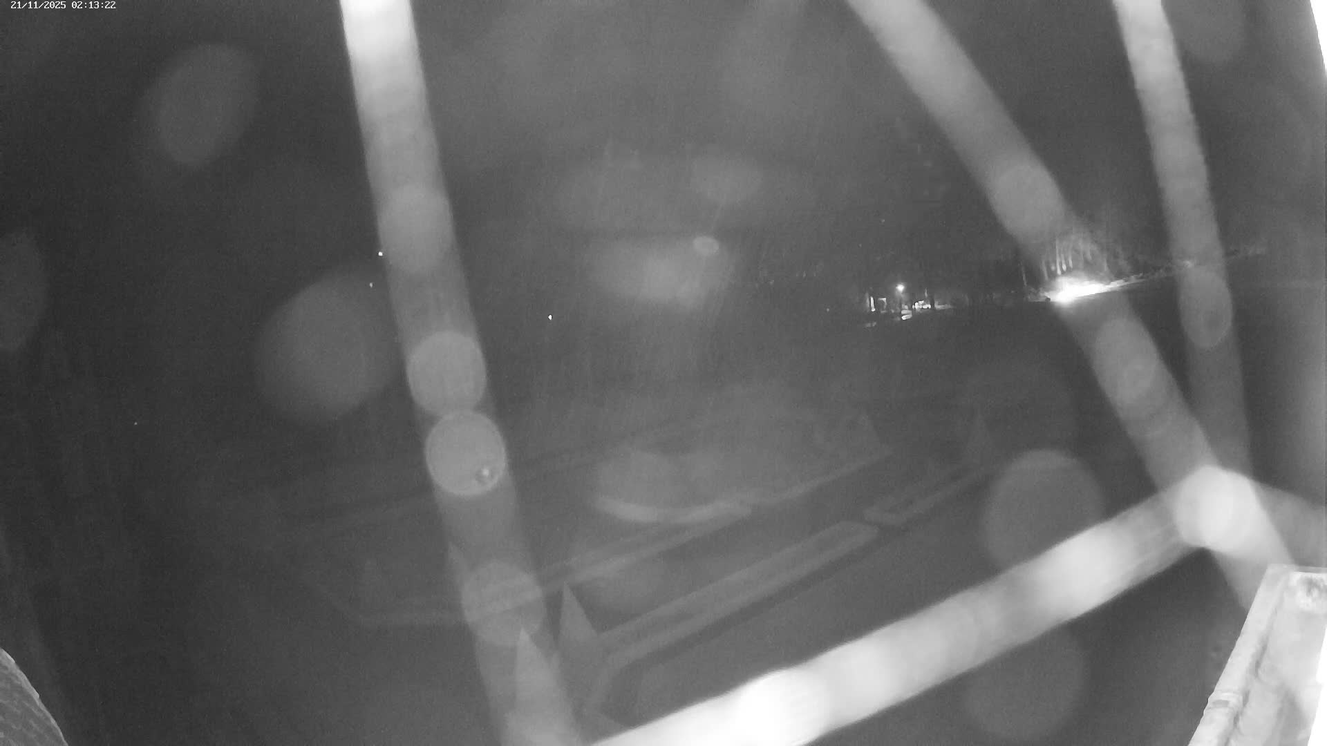 An overcast day reveals a formal garden with a central fountain, manicured lawns, and hedges, adjacent to a large building.