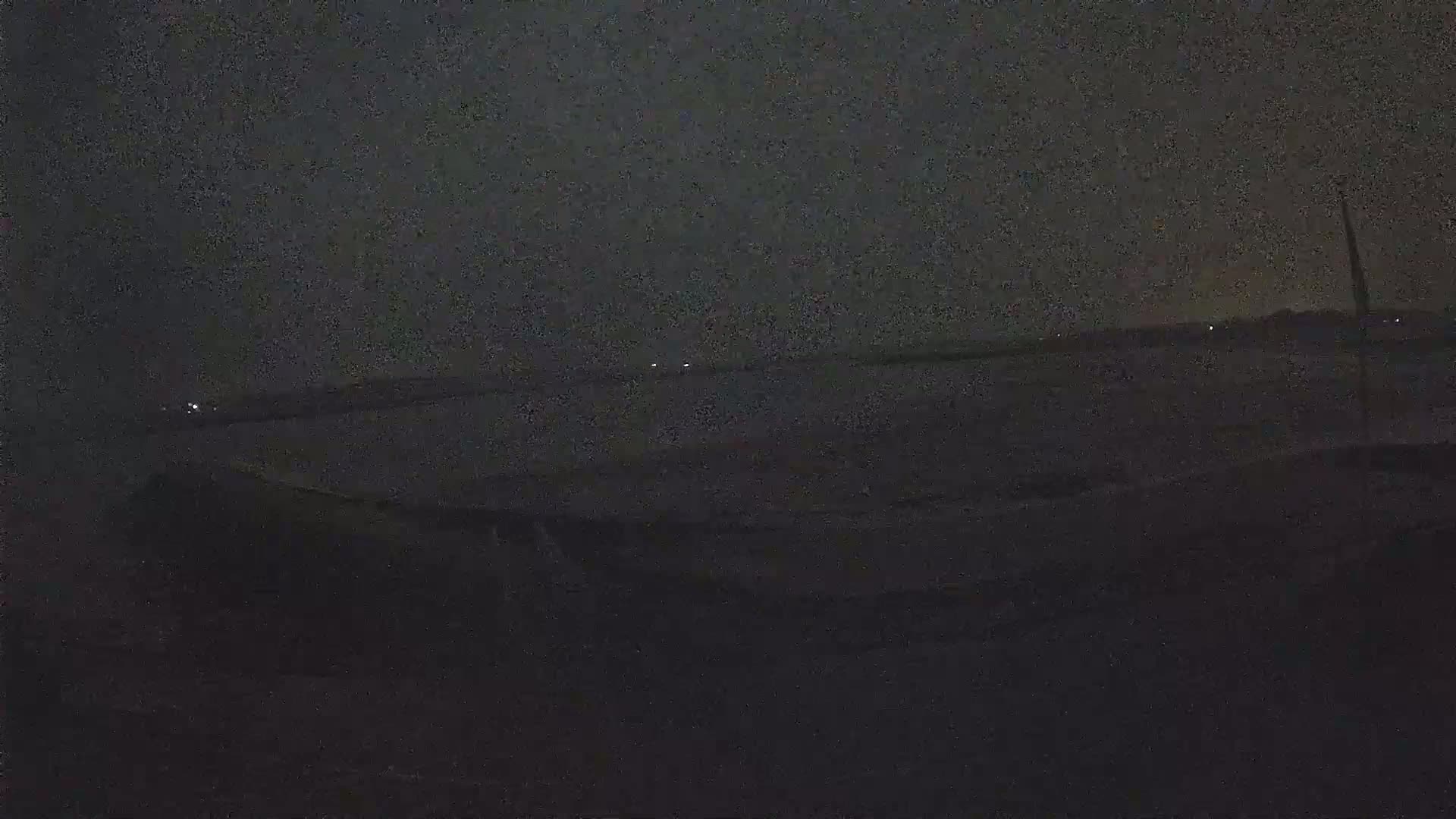 A dark, nighttime view of a calm body of water with a few distant lights visible on the horizon.