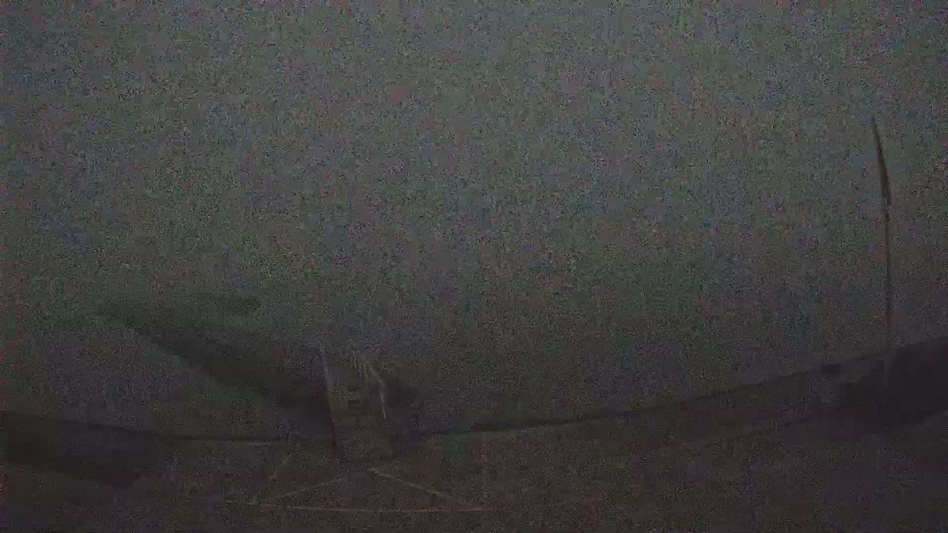 A blurry, dark image shows a possibly nighttime, outdoor scene with poor visibility.
